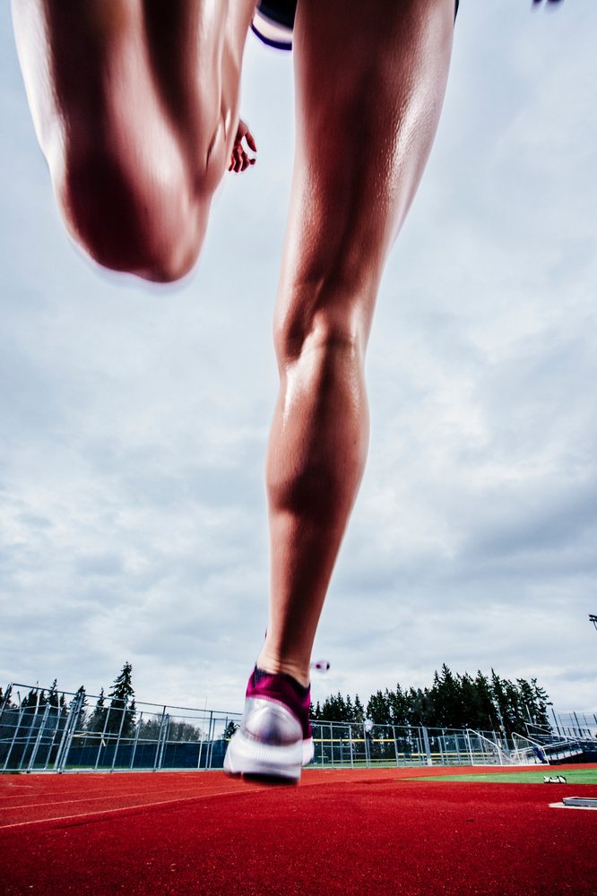 White runner sprinting on outdoor running track at sports facility
