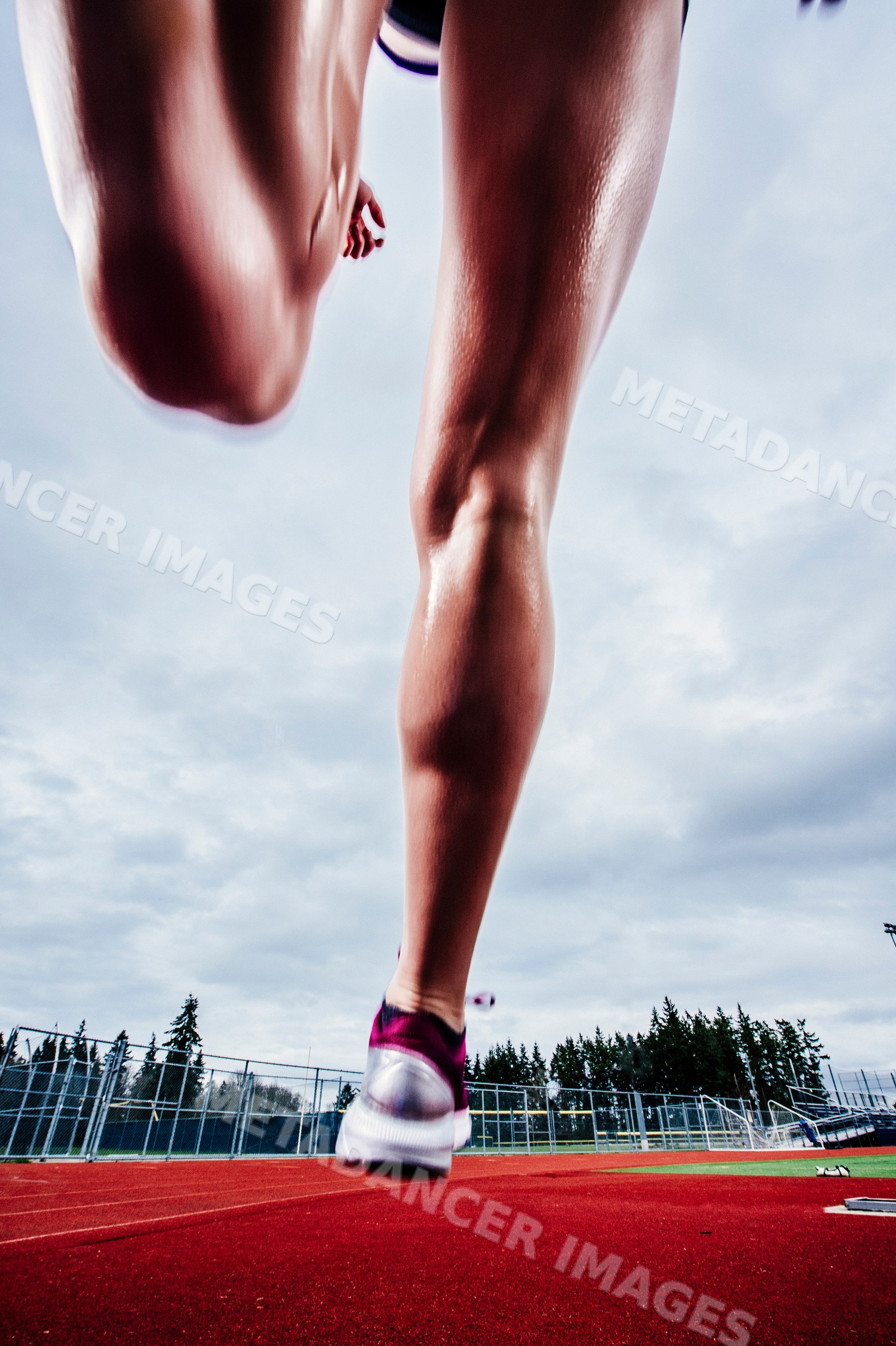 White runner sprinting on outdoor running track at sports facility