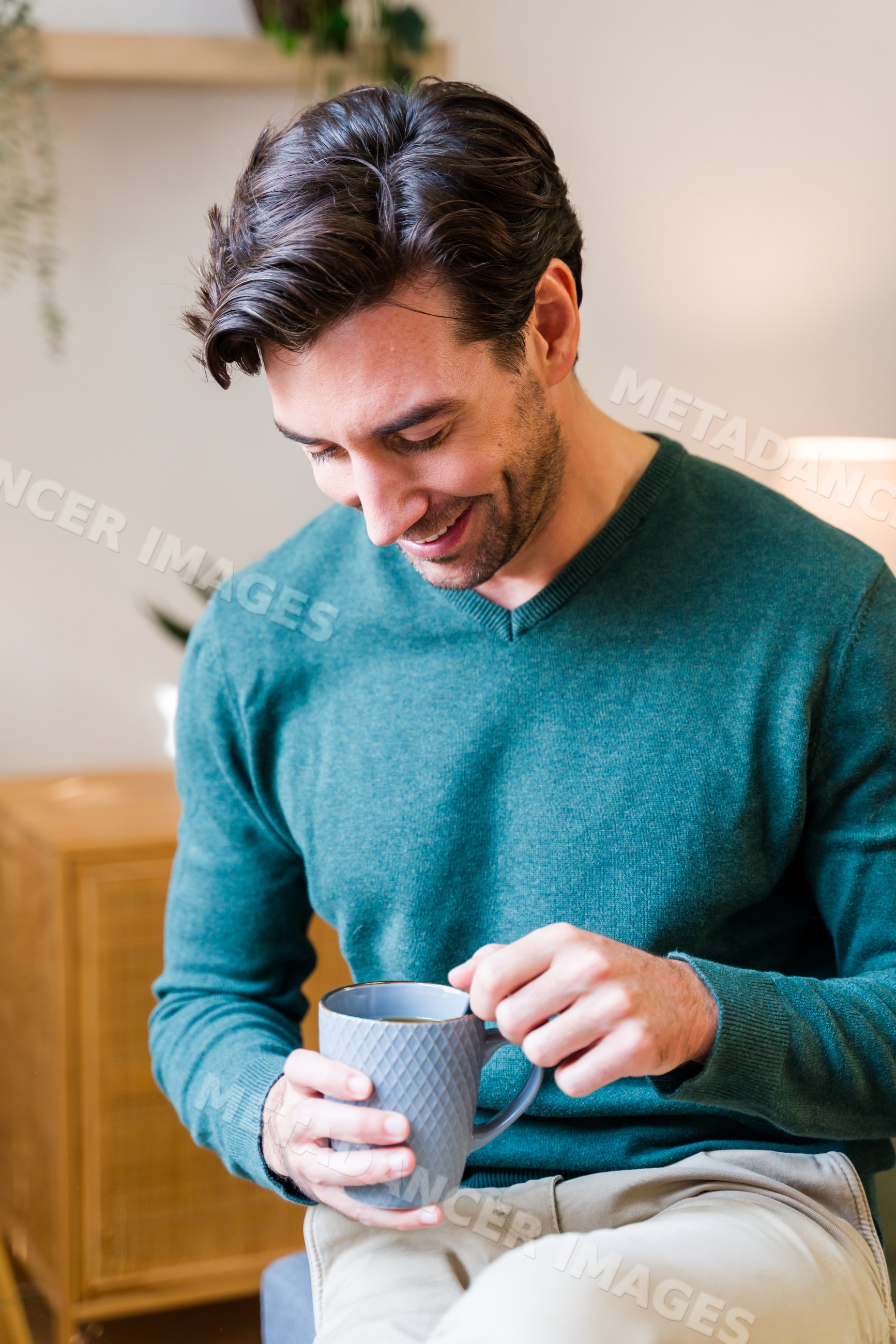 White man smiling and holding a mug indoors