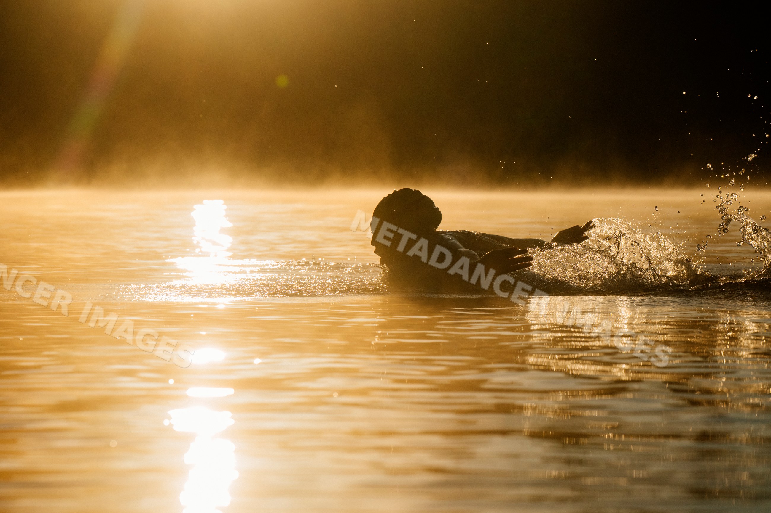 White person swimming in lake with sunlight reflecting on water