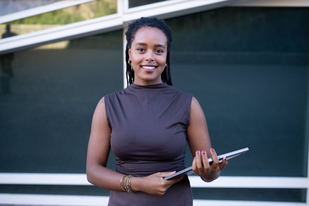 African American woman smiling while holding folder outdoors