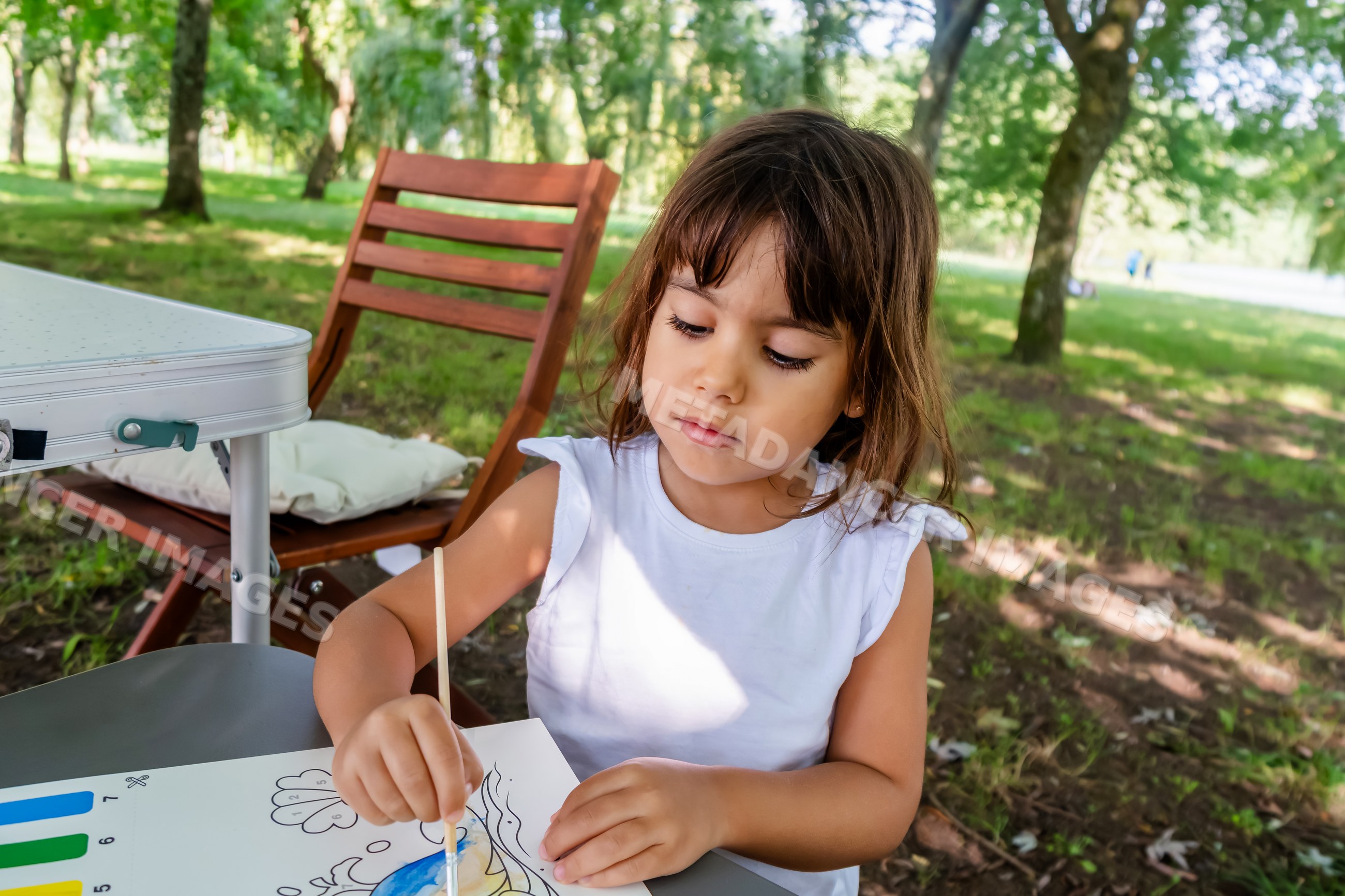 White child painting outdoors at a park table in a park