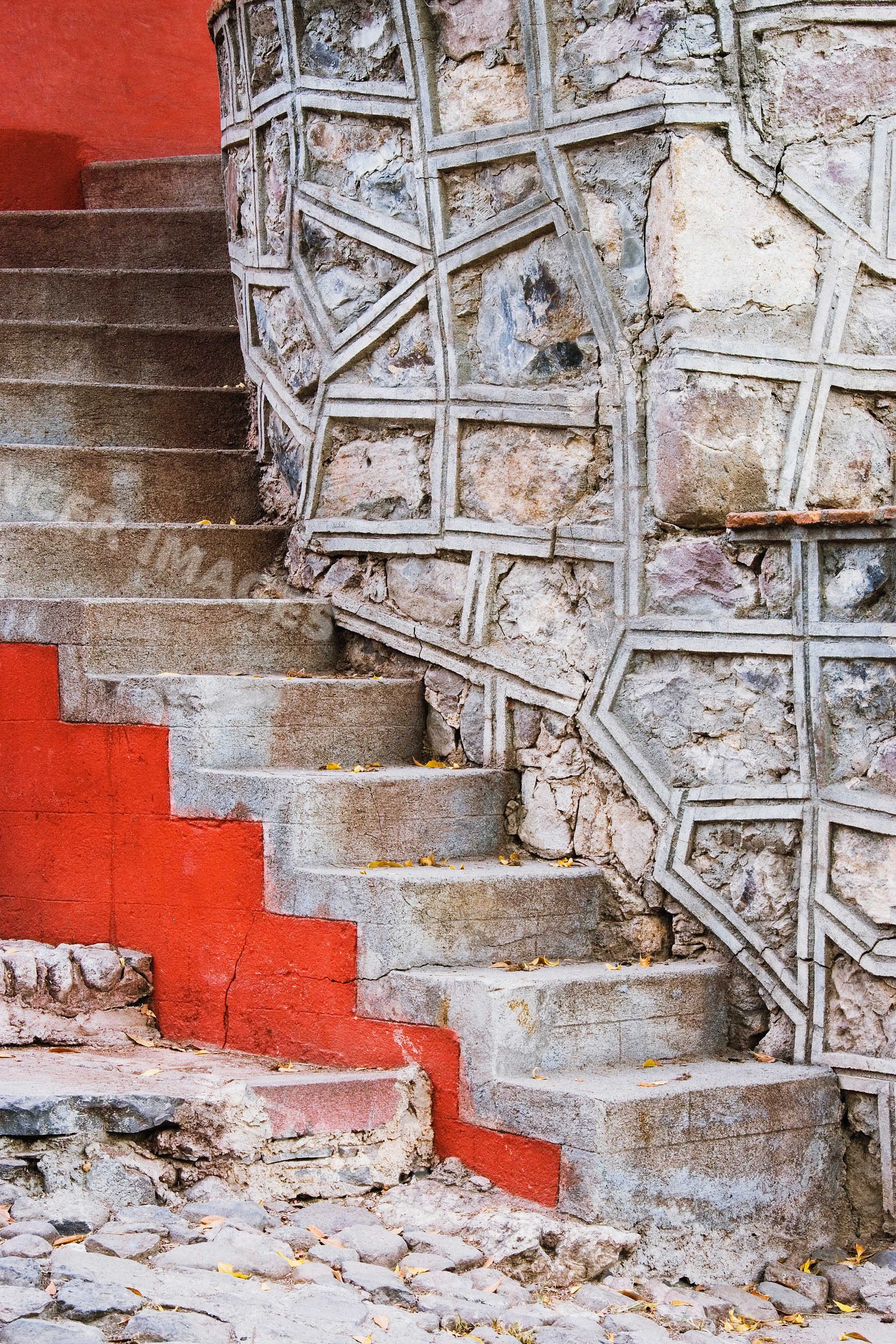 Stone steps with red painted edges beside stone masonry wall, mexico