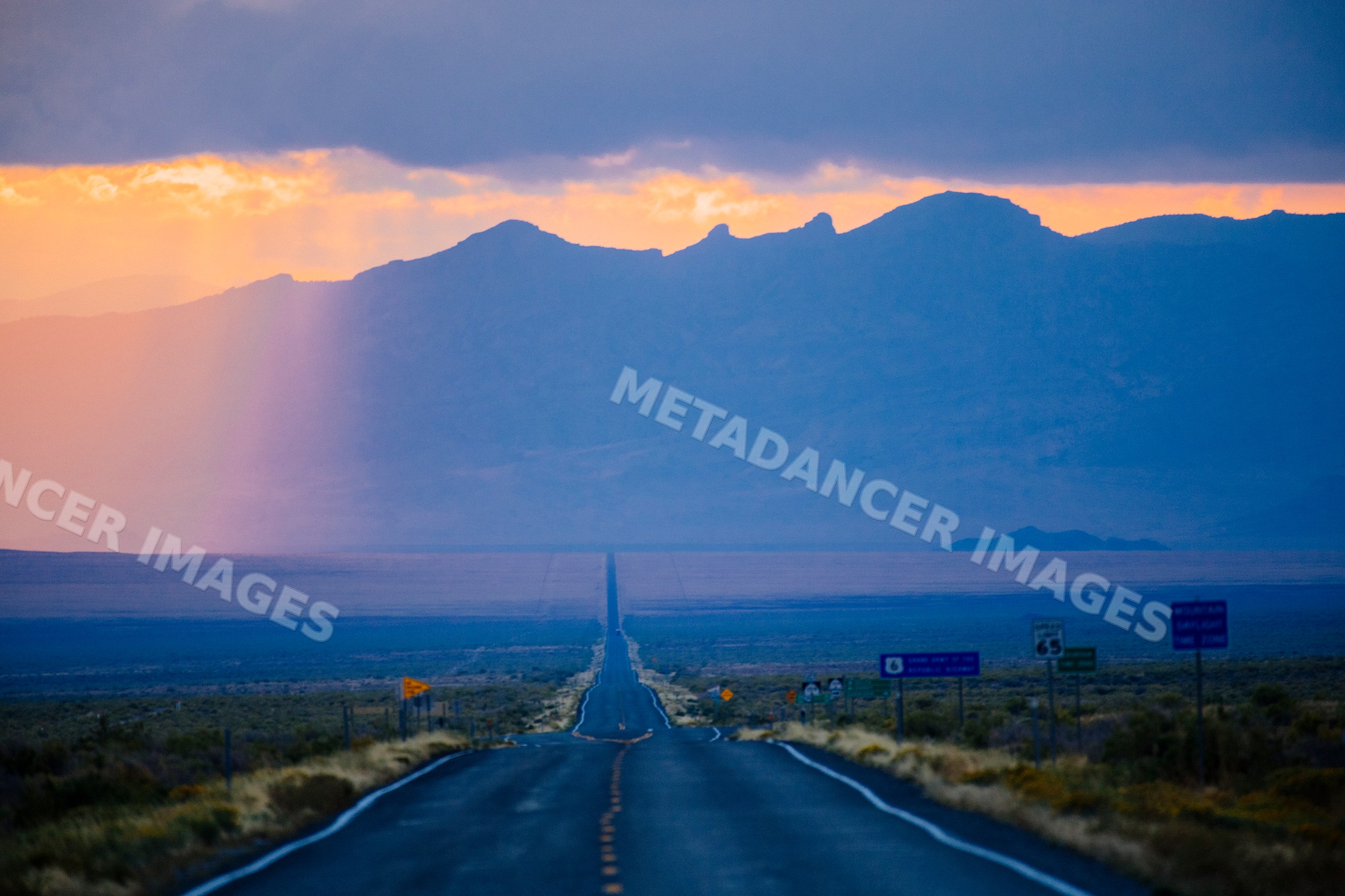 Road stretching into desert landscape with mountains