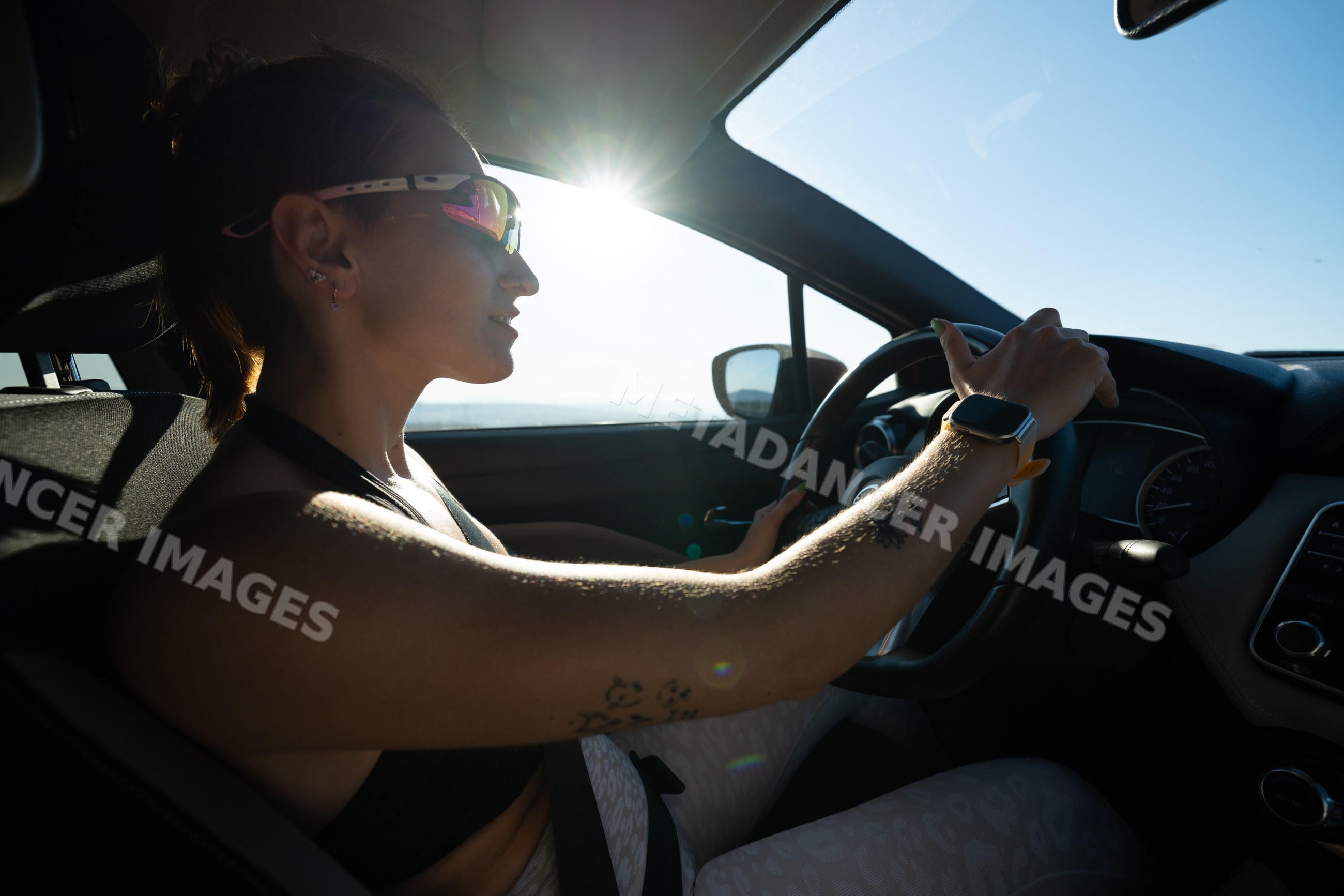 A white woman wearing sunglasses drives a car