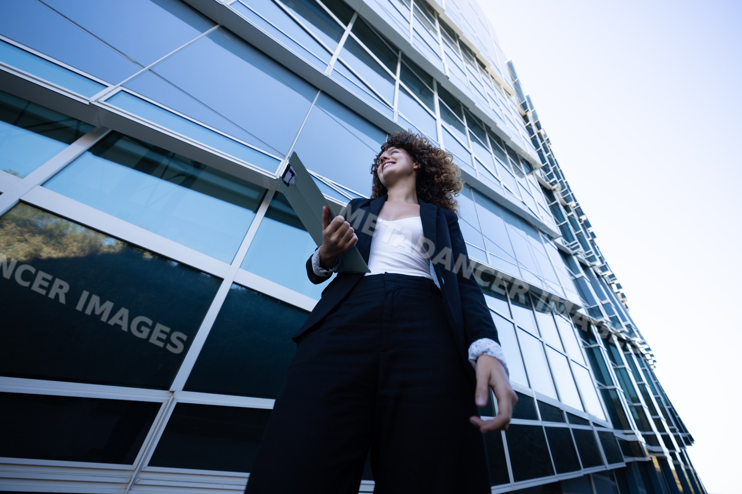 Businesswoman holding folder outside modern office building