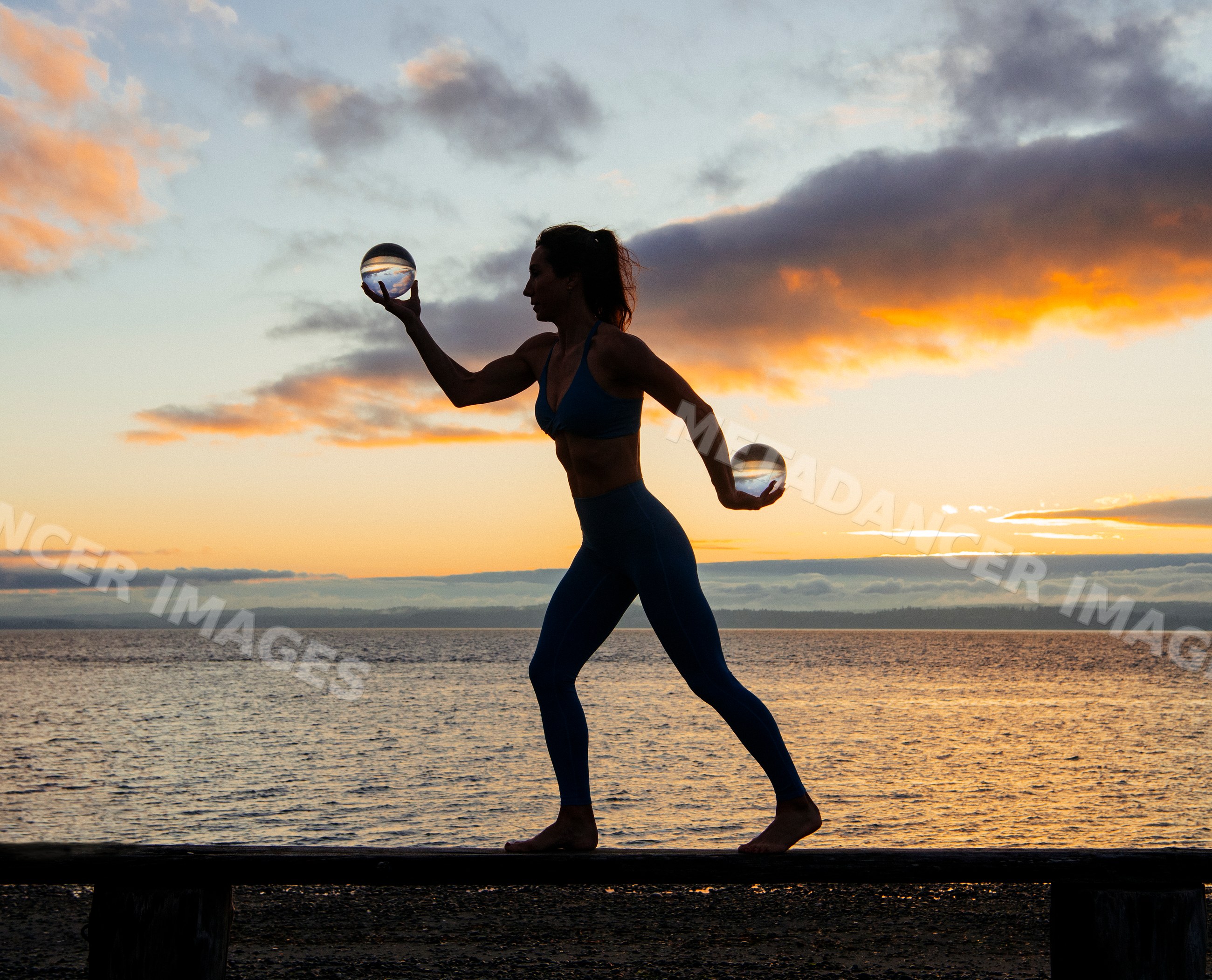 White woman holding glass spheres balancing on pier