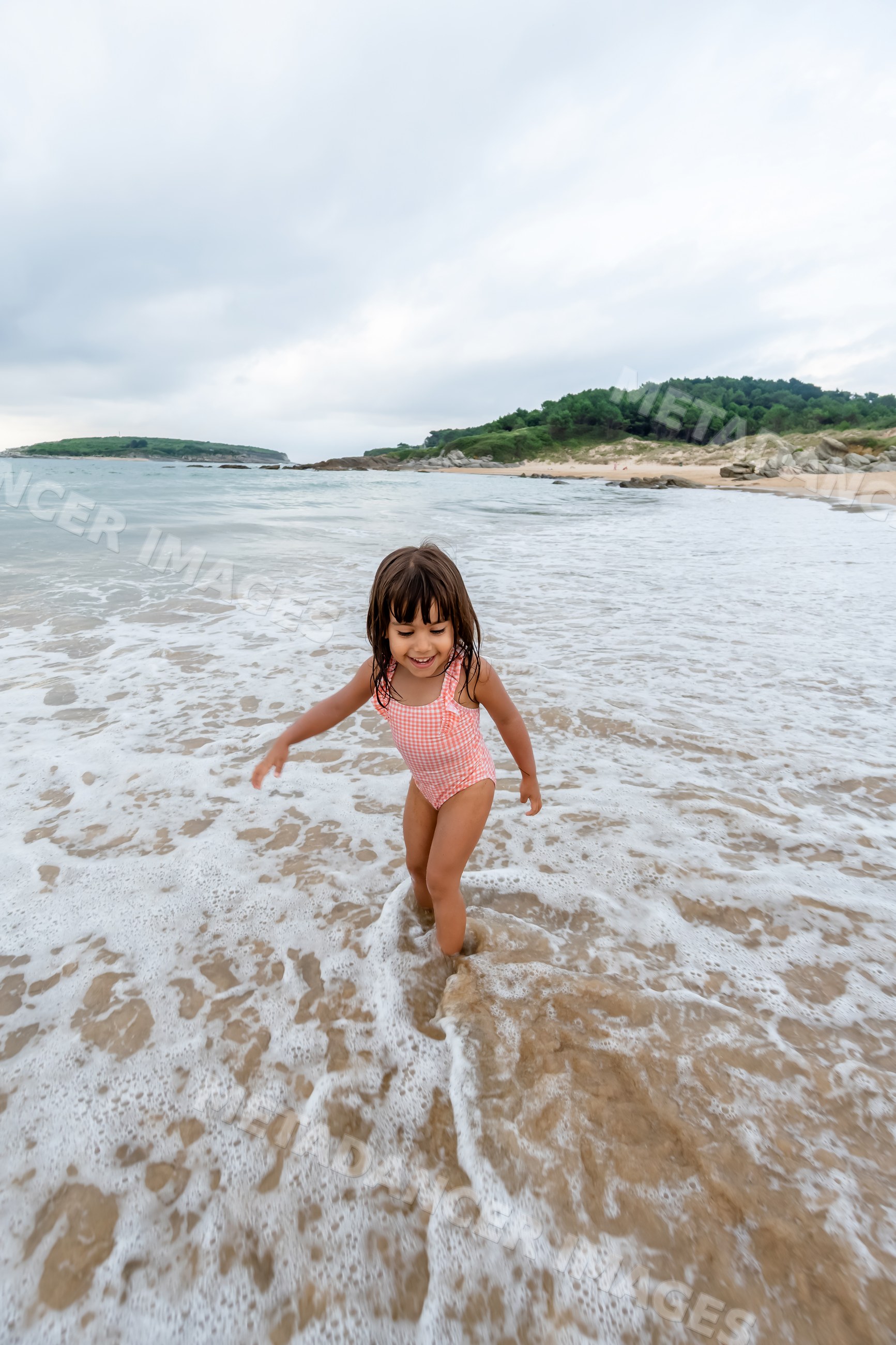 White child playing in ocean waves on sandy beach in a beach