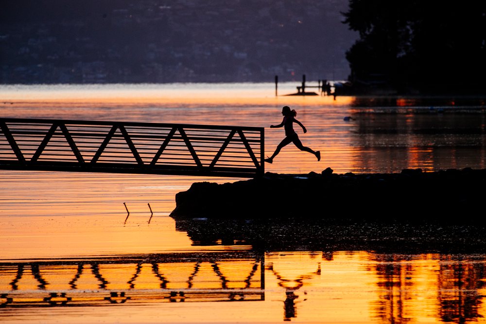 Silhouette of Pacific Islander woman jumping from shore to dock