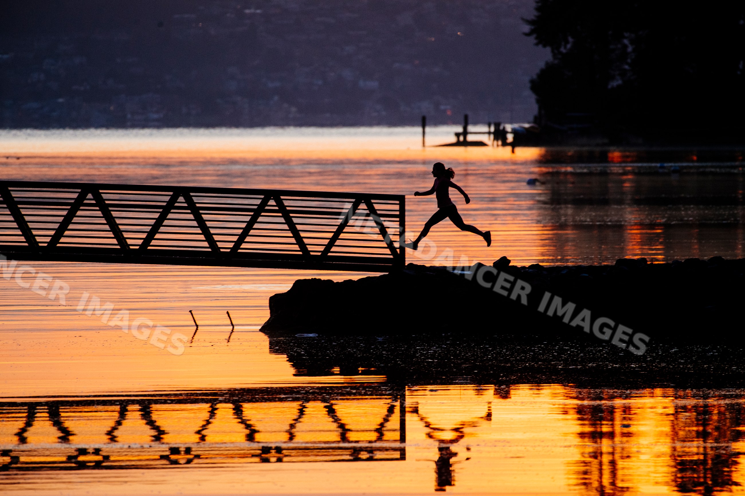 Silhouette of Pacific Islander woman jumping from shore to dock