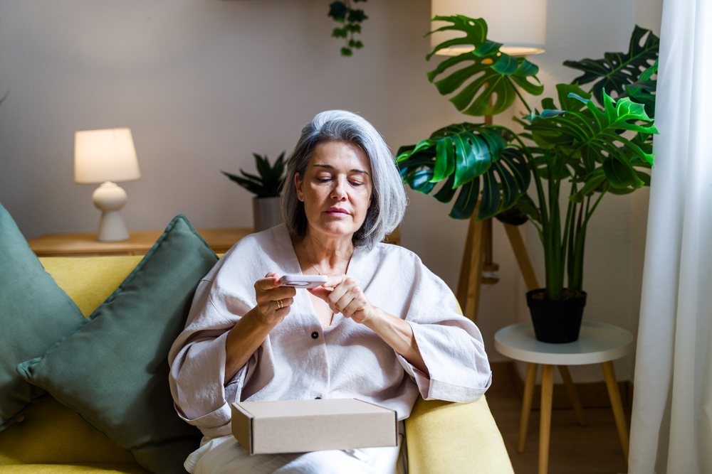 Middle-aged white woman using smartphone on yellow sofa