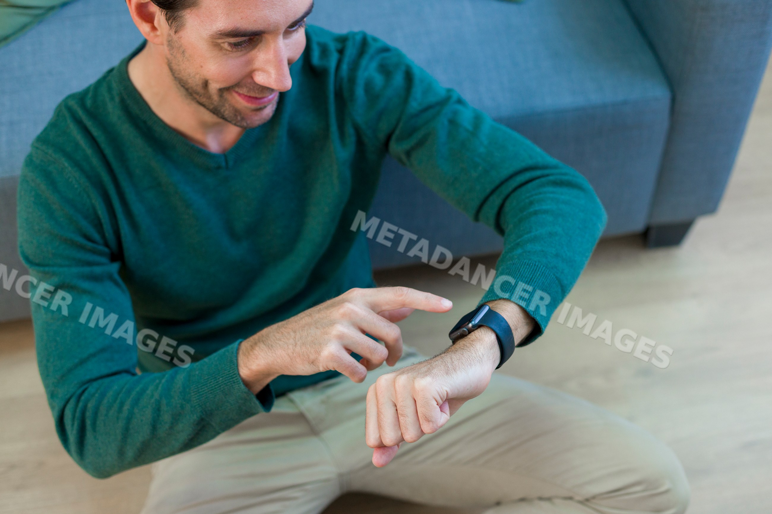 White man sitting on floor using smartwatch setting