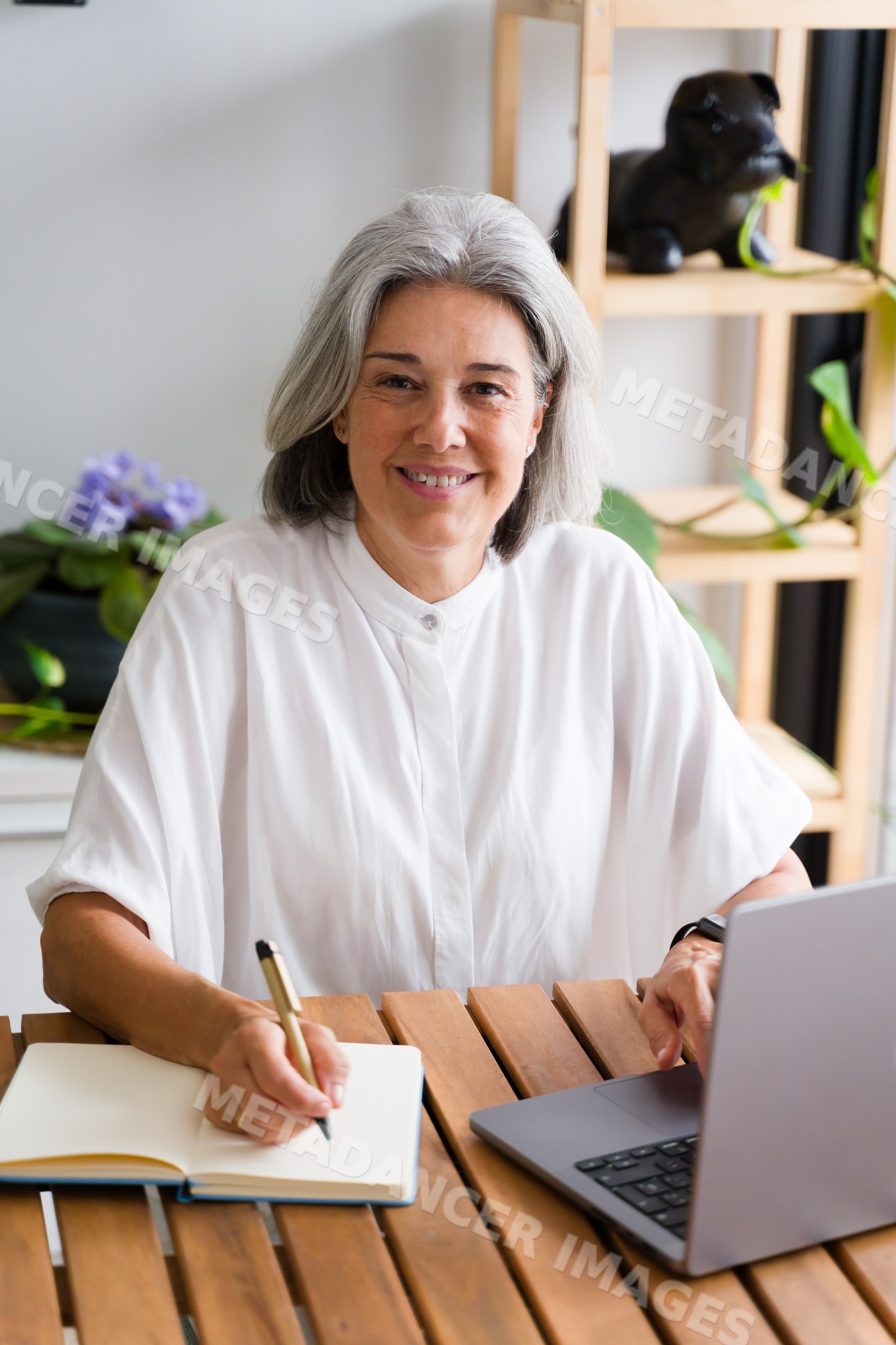 Middle aged white woman writing and working on laptop