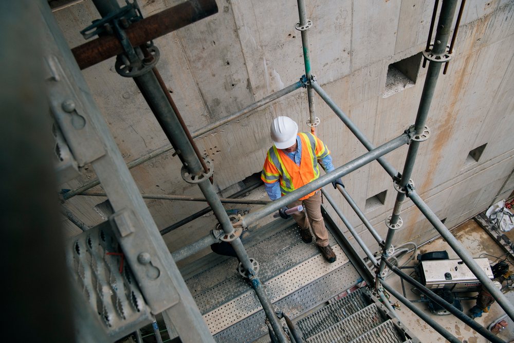 Two white construction workers communicate on scaffolding stairs