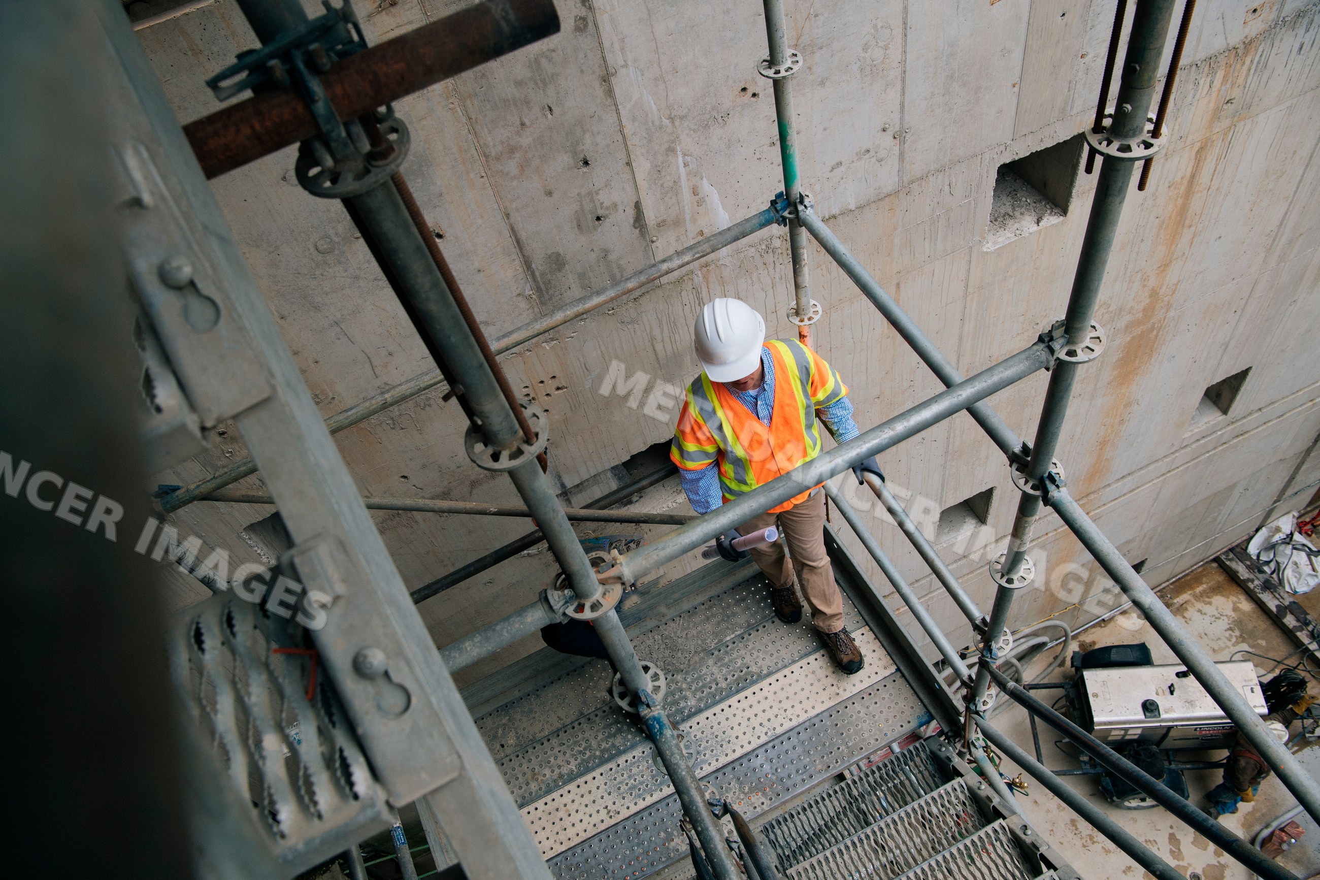 Two construction white workers communicate on scaffolding stairs