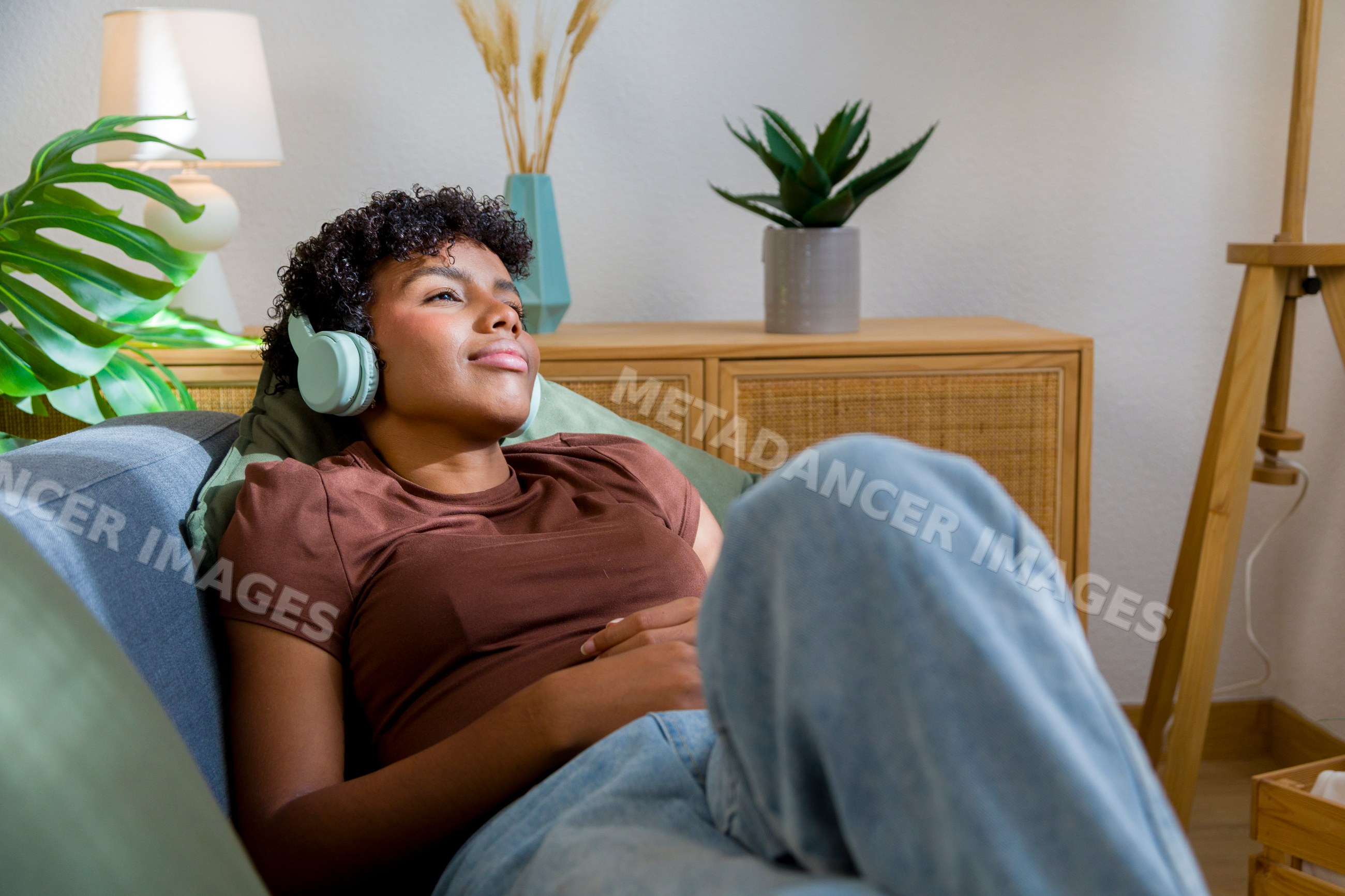 African American woman relaxing with headphones on sofa