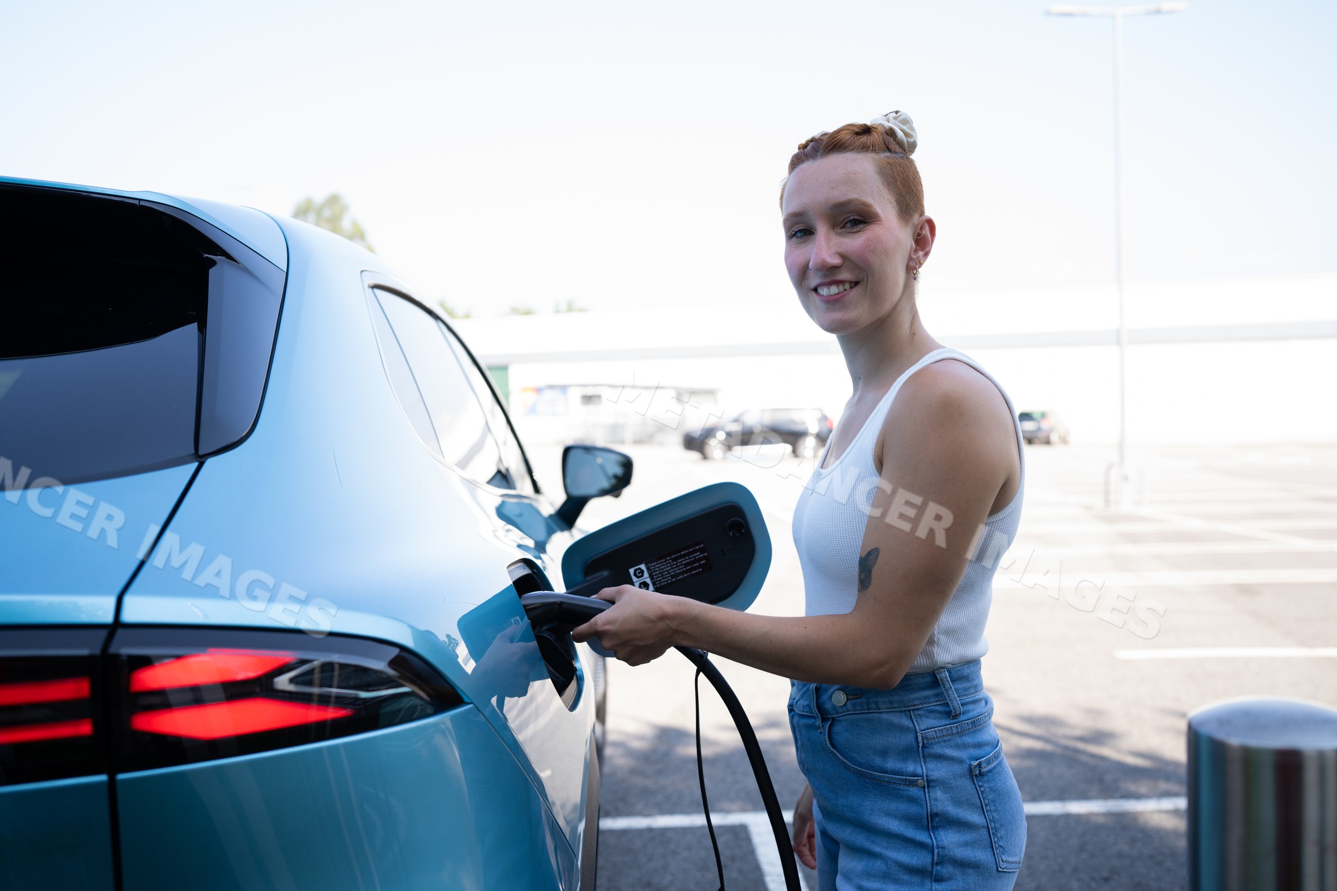 White Woman charging an electric vehicle at a public charging station