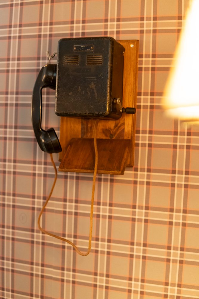 Vintage corded telephone mounted on wooden base in retro setting