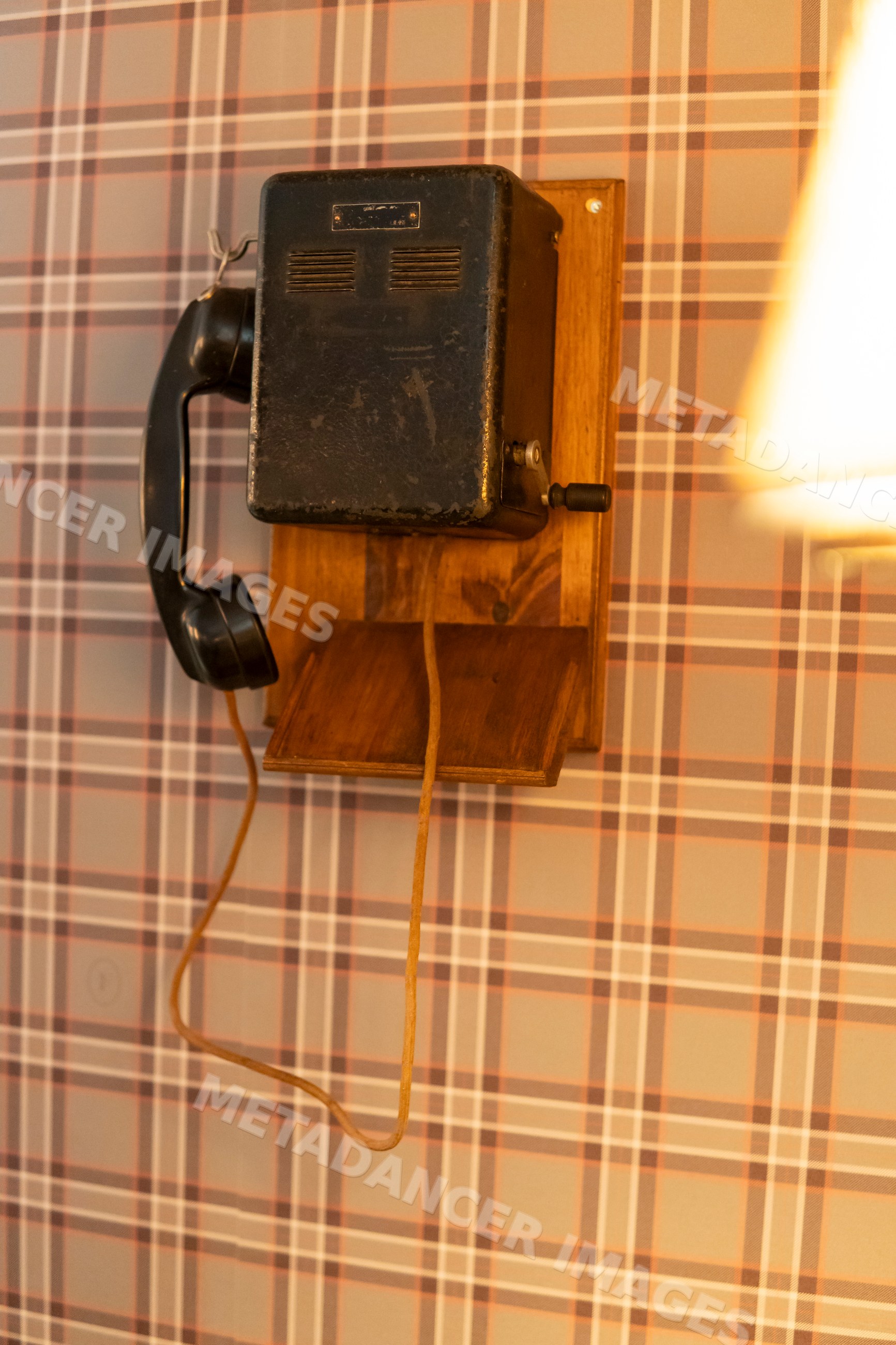 Vintage corded telephone mounted on wooden base in retro setting