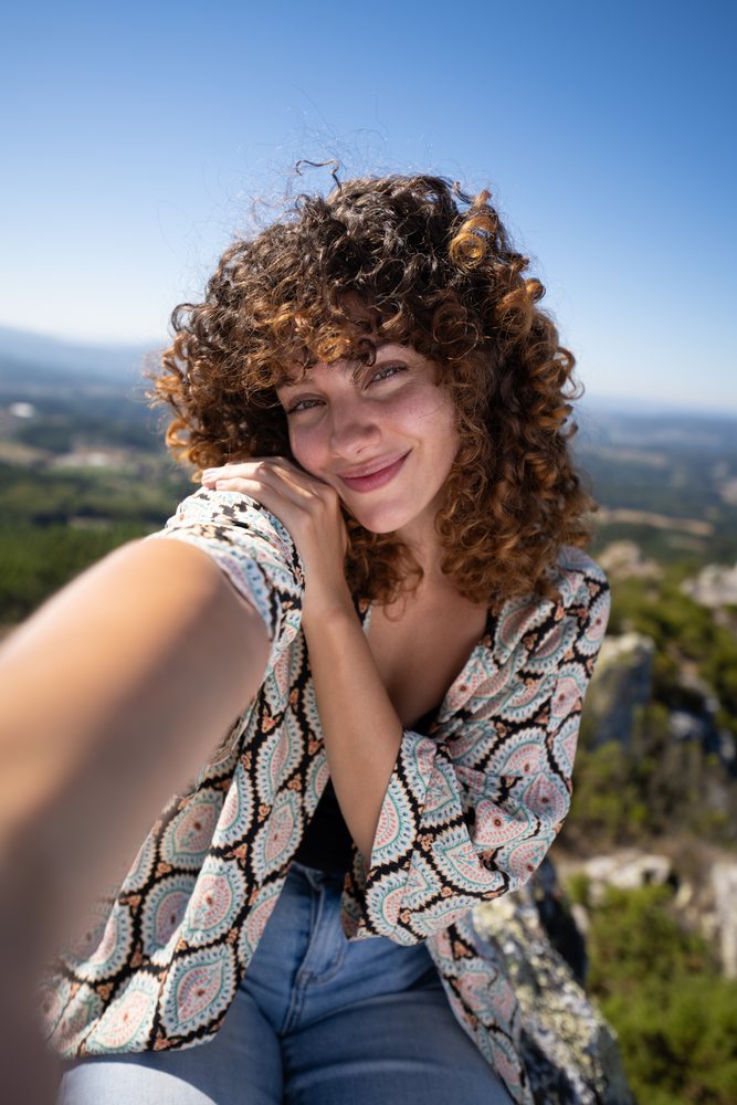 White woman taking selfie atop Pico Sacro mountain in Galicia Spain