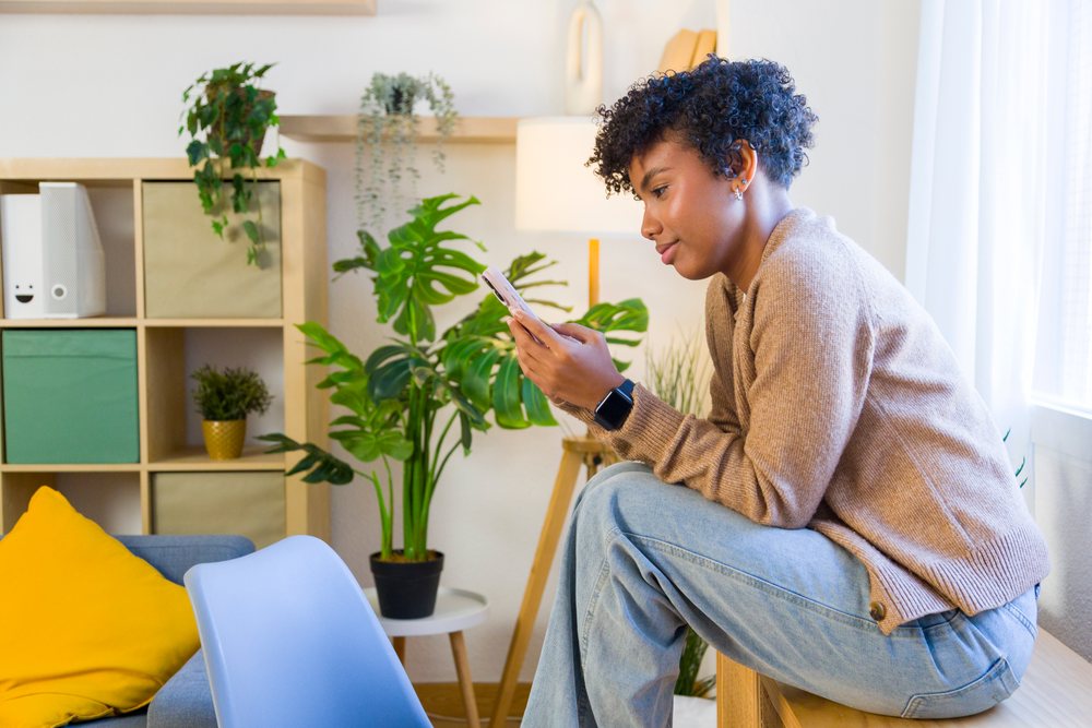 Young African American woman using smartphone indoors