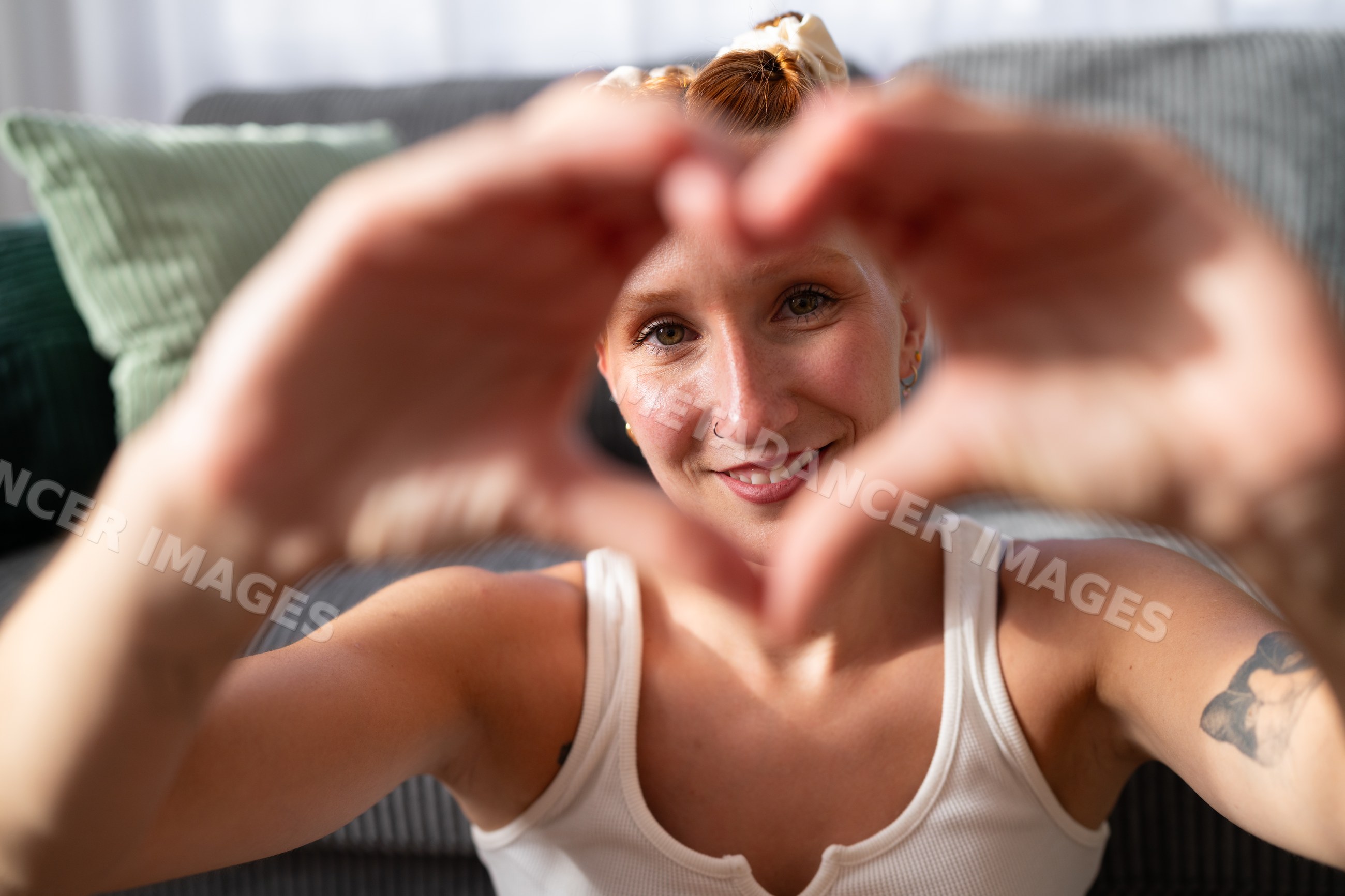 A young white woman forms a heart shape with her hands