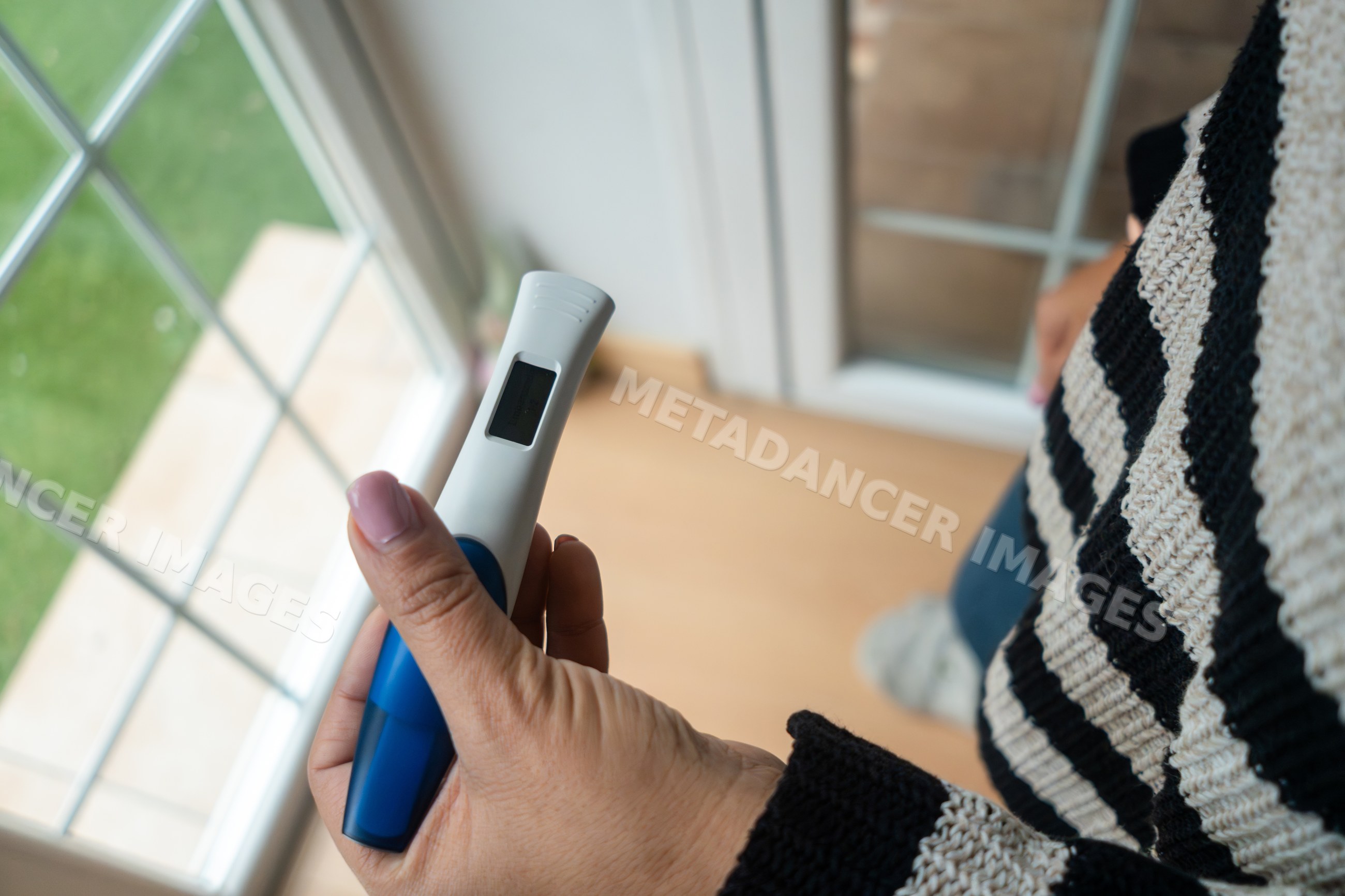 Woman reads pregnancy test result in her home by a window