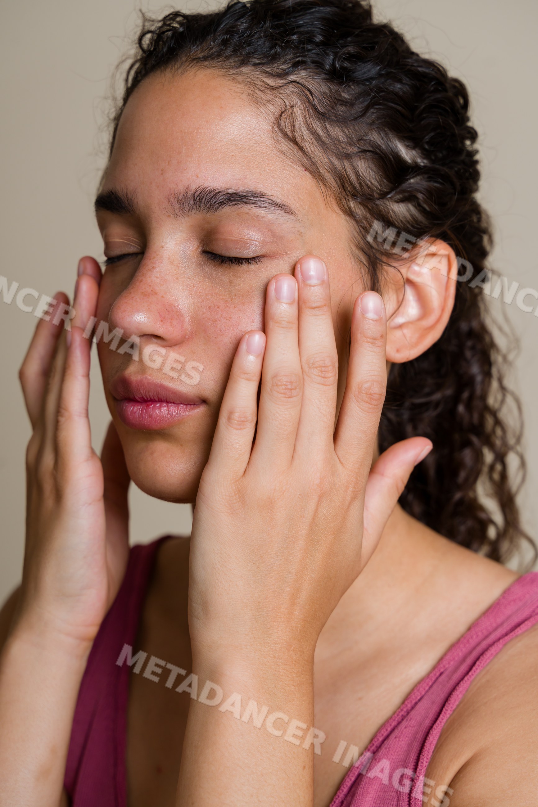 Hispanic woman gently touching face with closed eyes