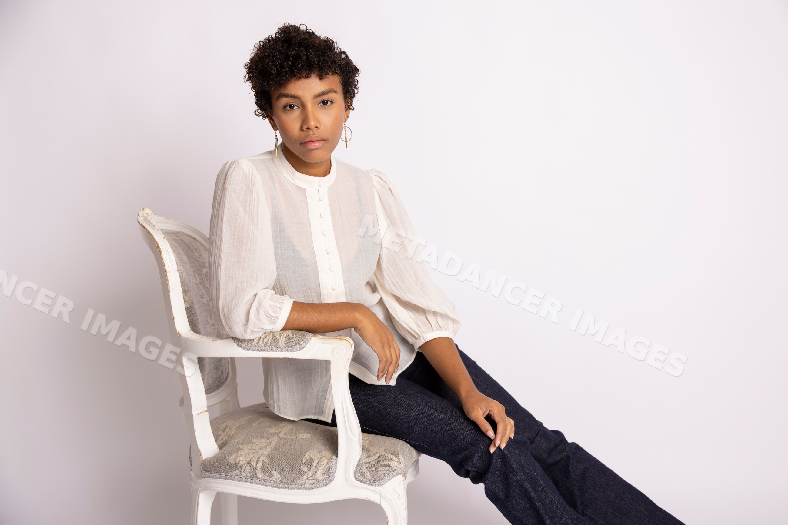 Young Hispanic woman sitting on white antique wooden chair