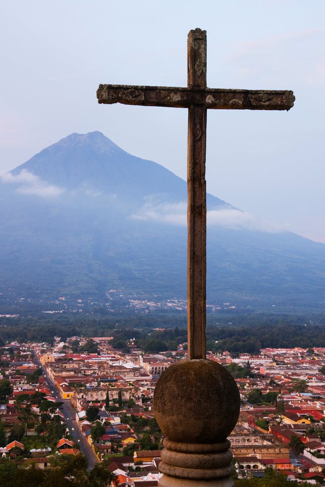 Stone cross overlooking antigua with volcan agua volcano