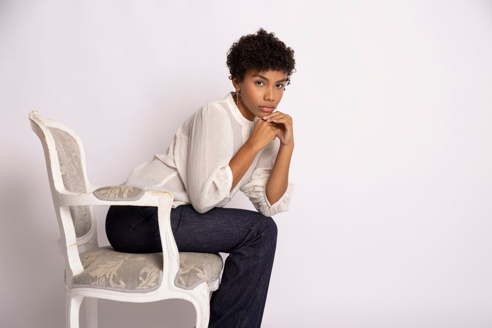 Hispanic woman sitting thoughtfully on a vintage chair