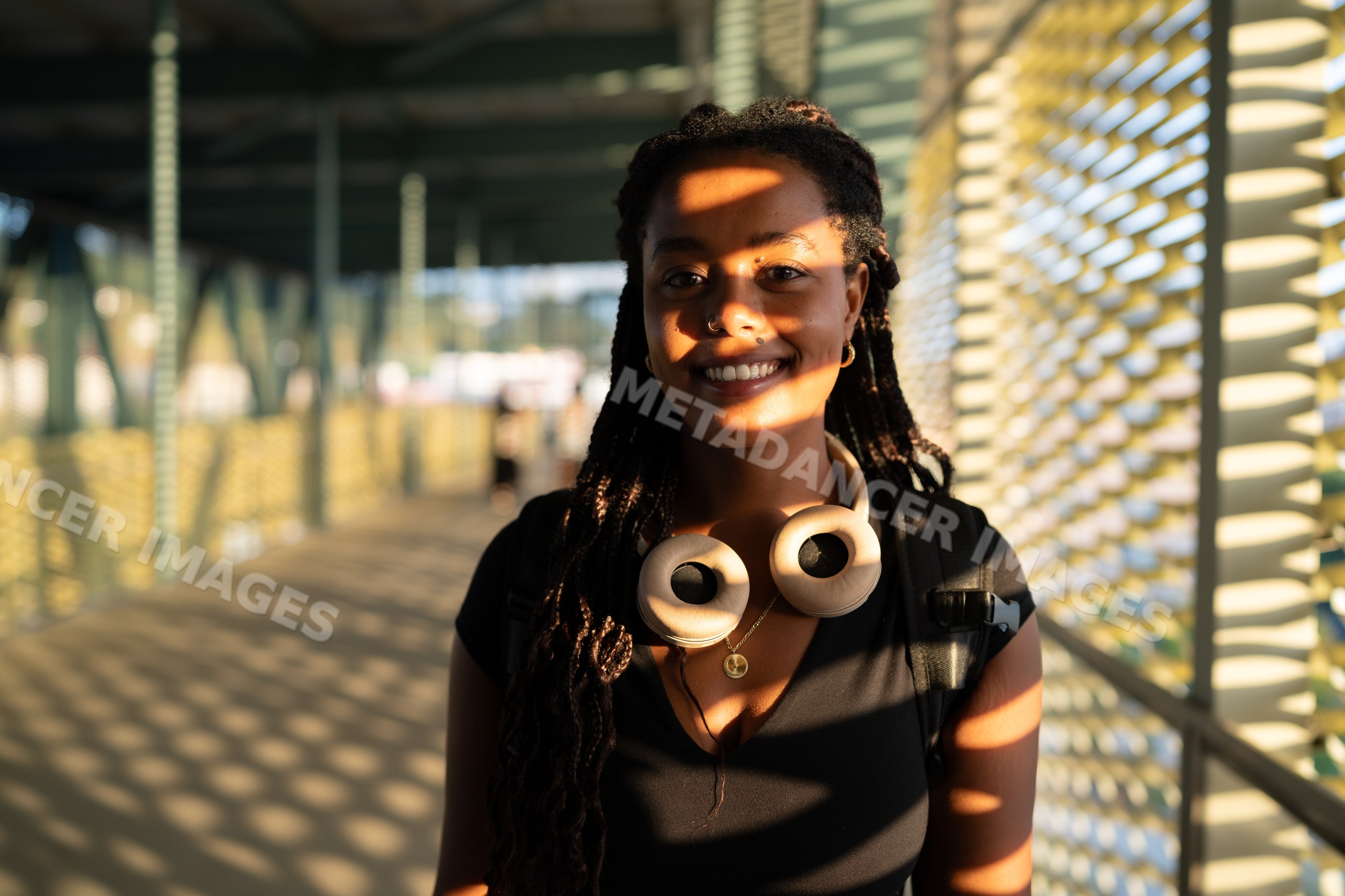 A young African American woman smiling on a sunlit urban walkway