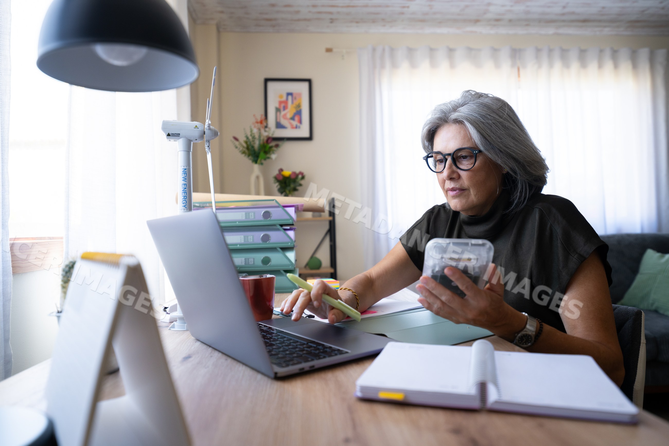Mature white woman working on laptop and calculator in home office
