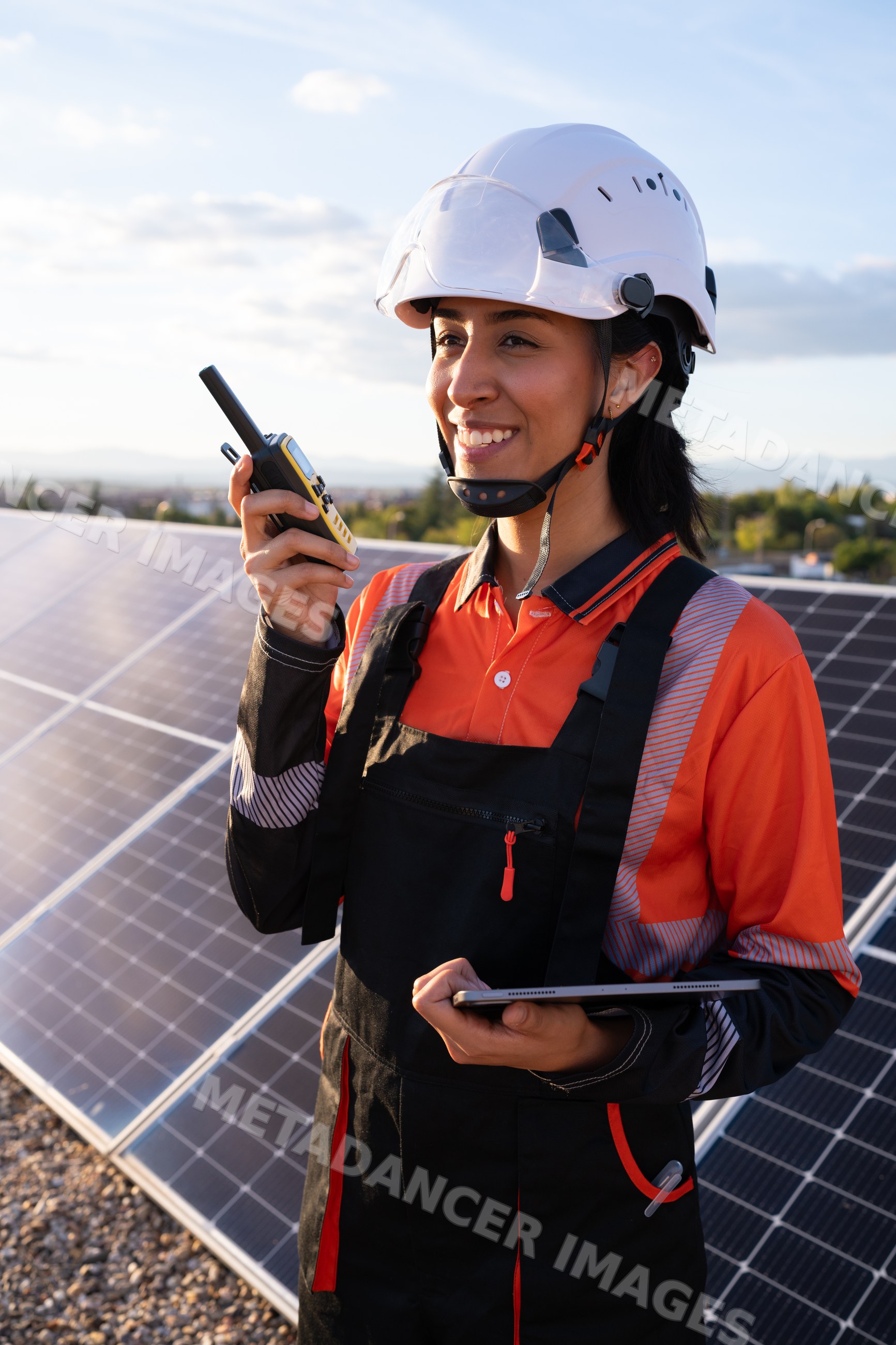 Hispanic woman worker using walkie-talkie by solar panels outdoors