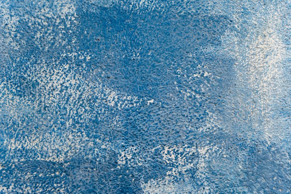 Blue textured painted surface with abstract coarse pattern