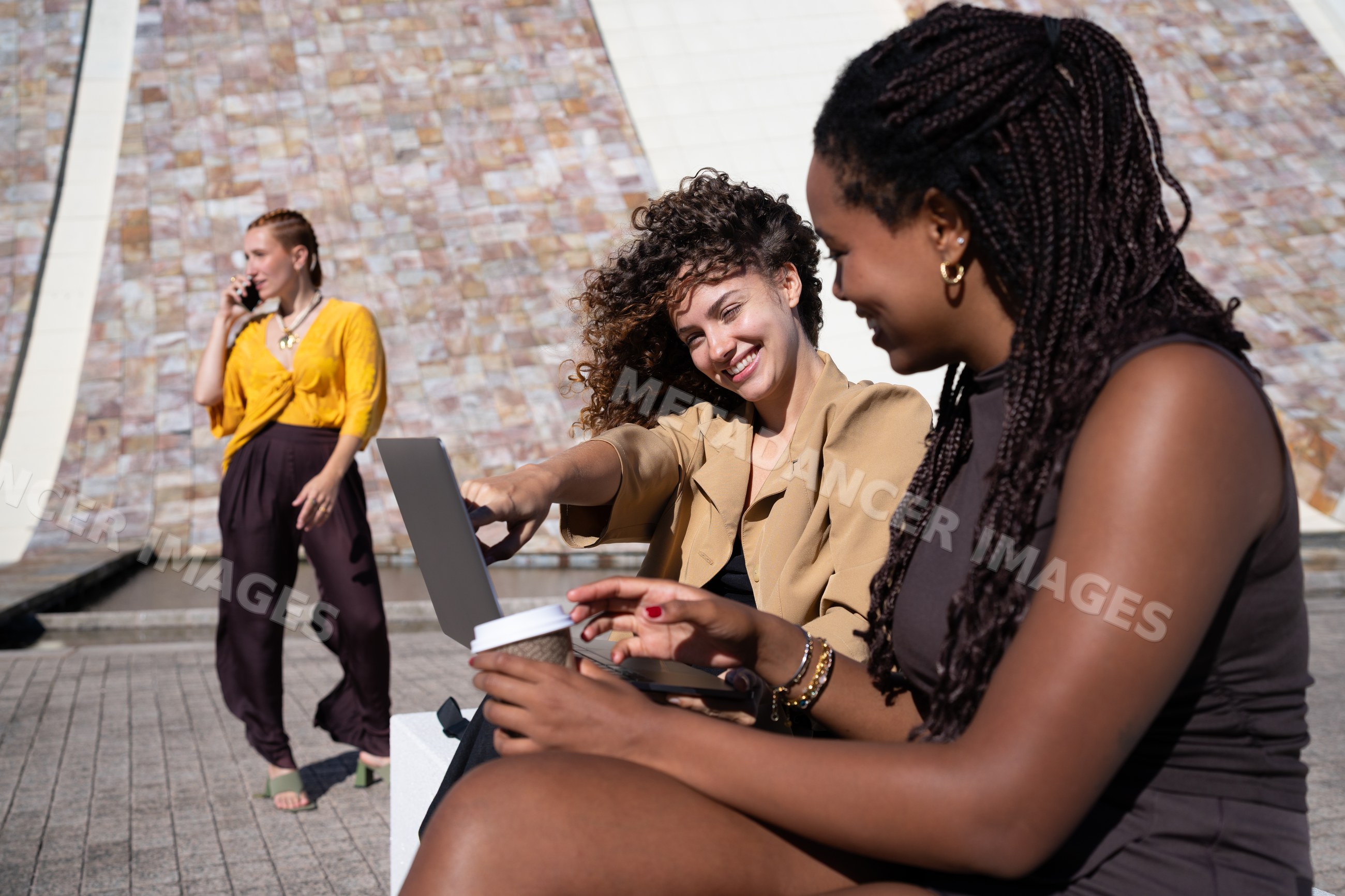 African American and white women engaging with laptop and coffee