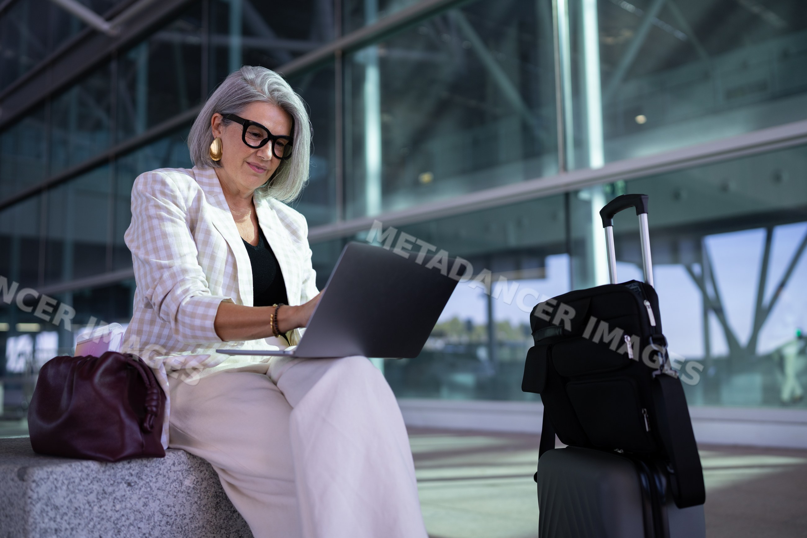 Businesswoman working on laptop with luggage