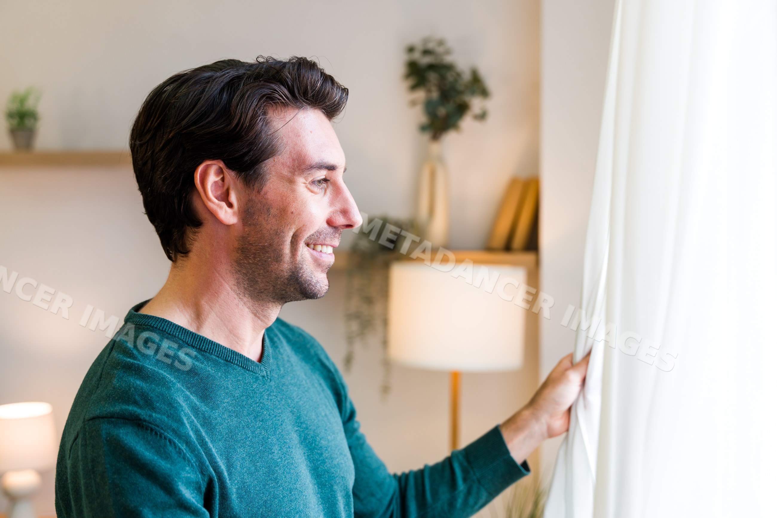 White man smiling and pulling back curtain