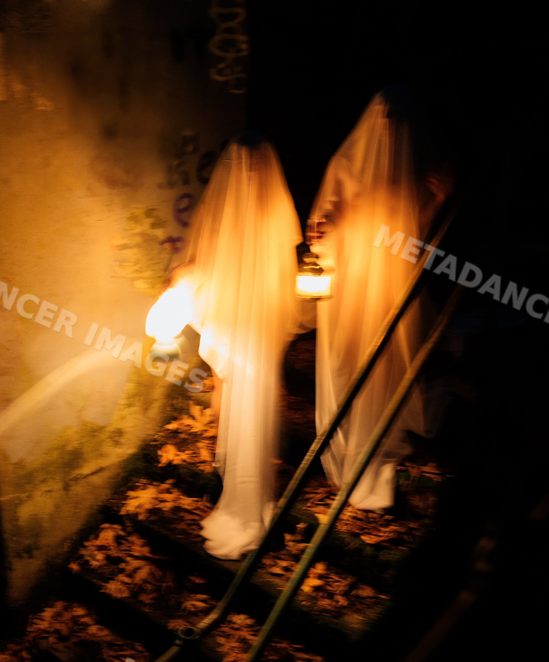 Ghost figures holding lanterns descending outdoor stairs at night