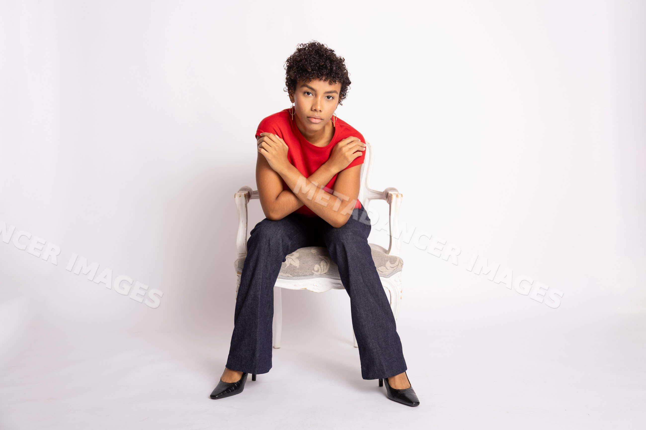 Young Hispanic woman sitting cross-armed on chair