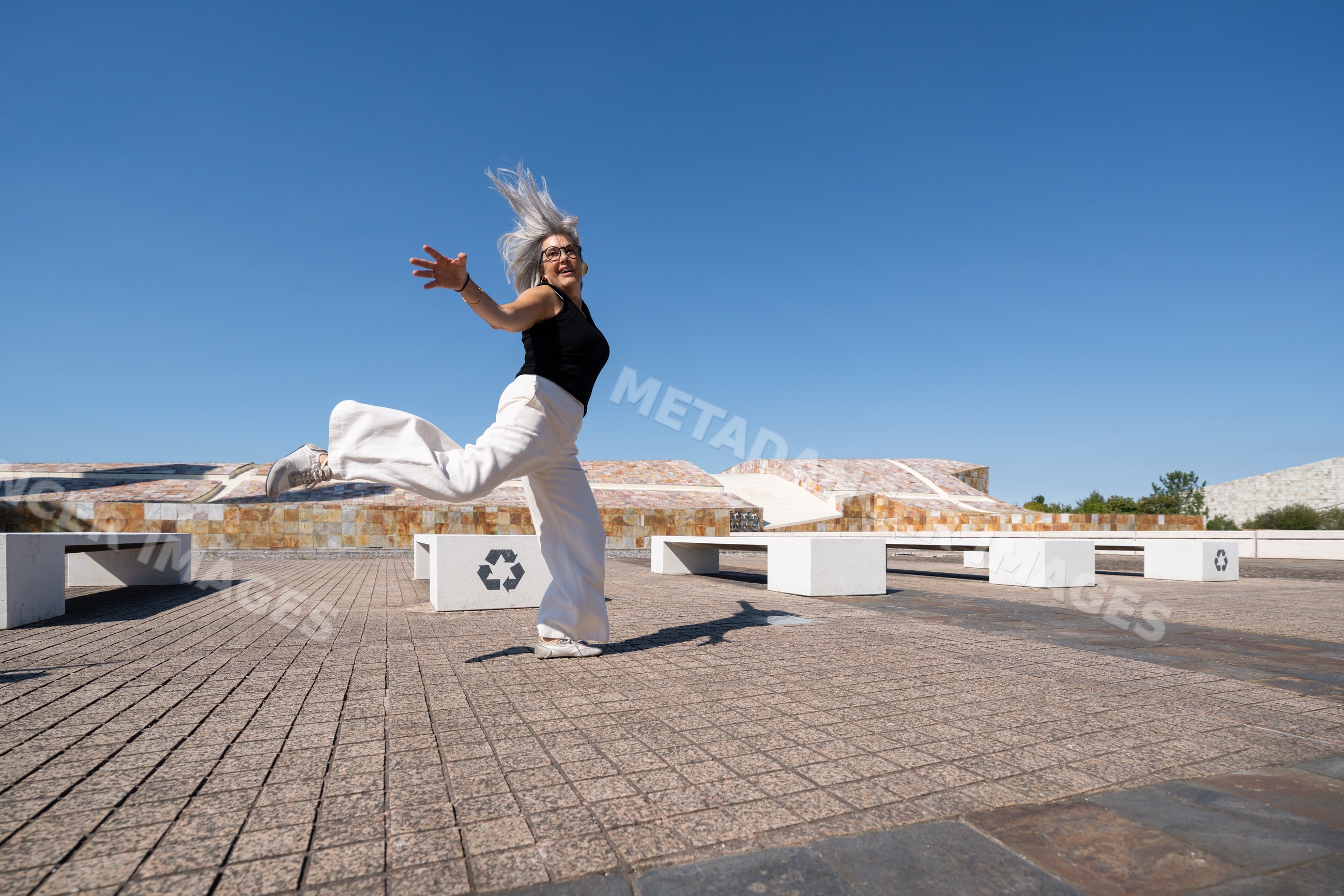 White woman jumping joyfully in a sunlit public square