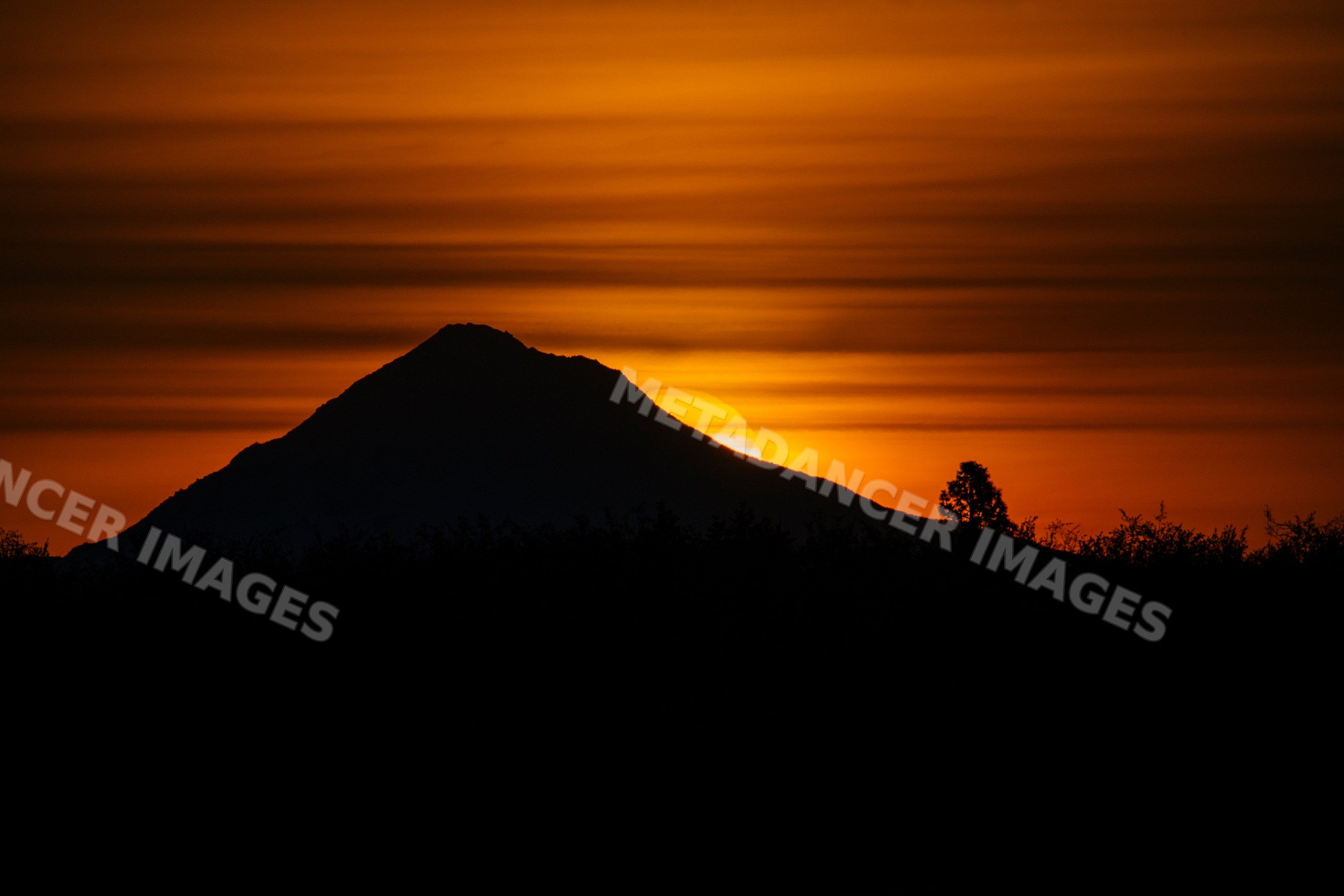 Mountain silhouette at sunset with glowing orange sky