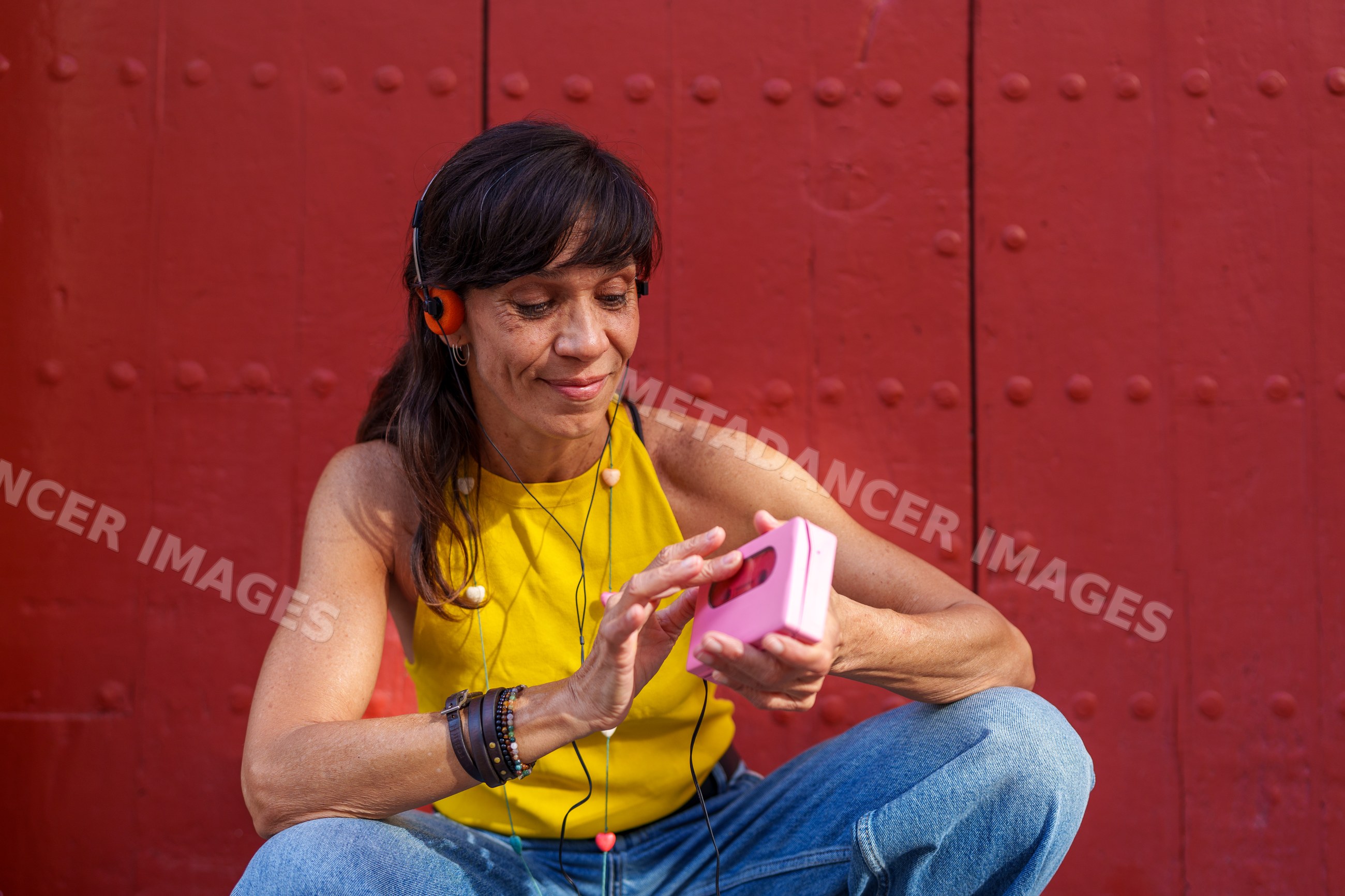 Hispanic woman sitting outdoors listening to music with headphones