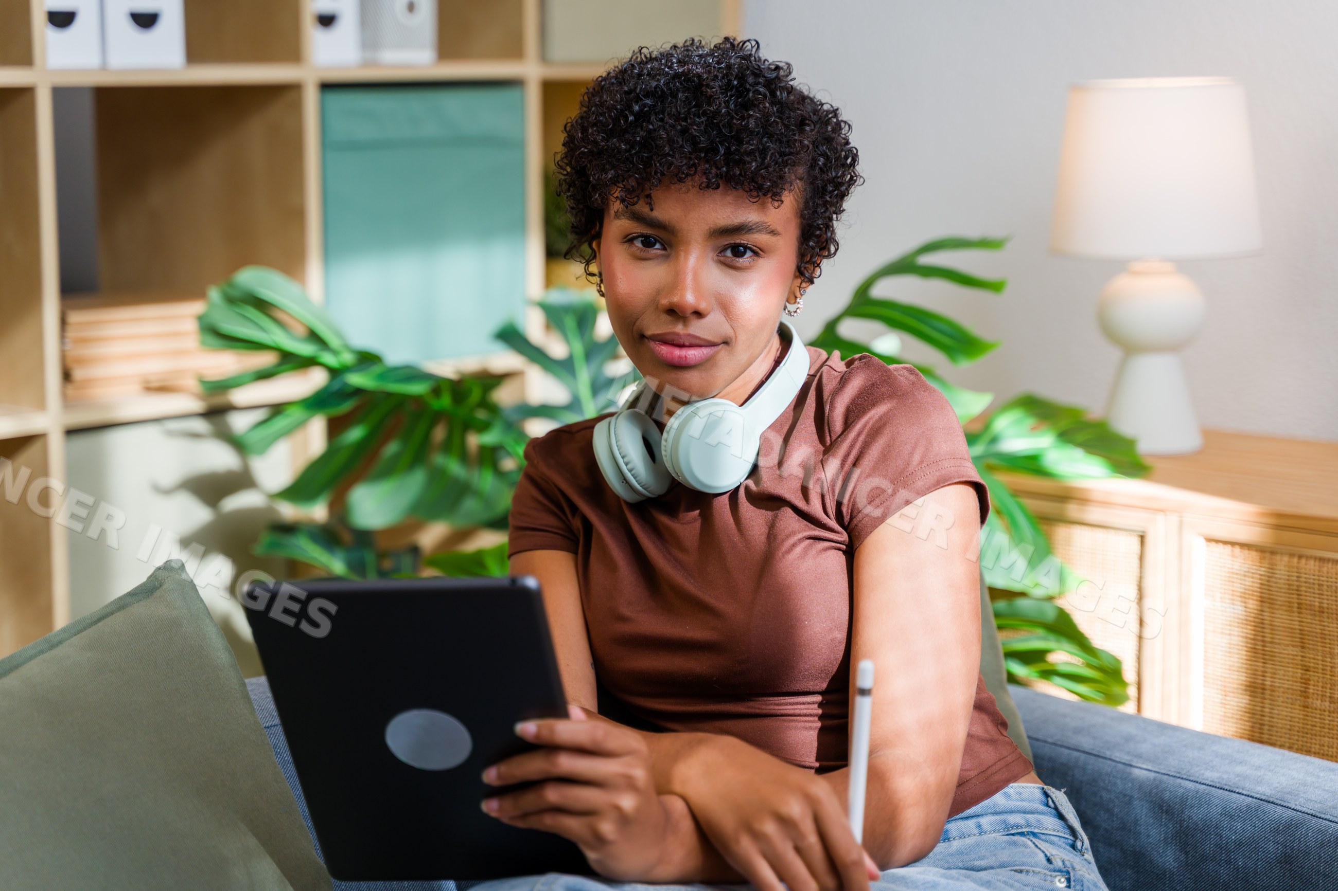 African American woman with headphones on couch using tablet