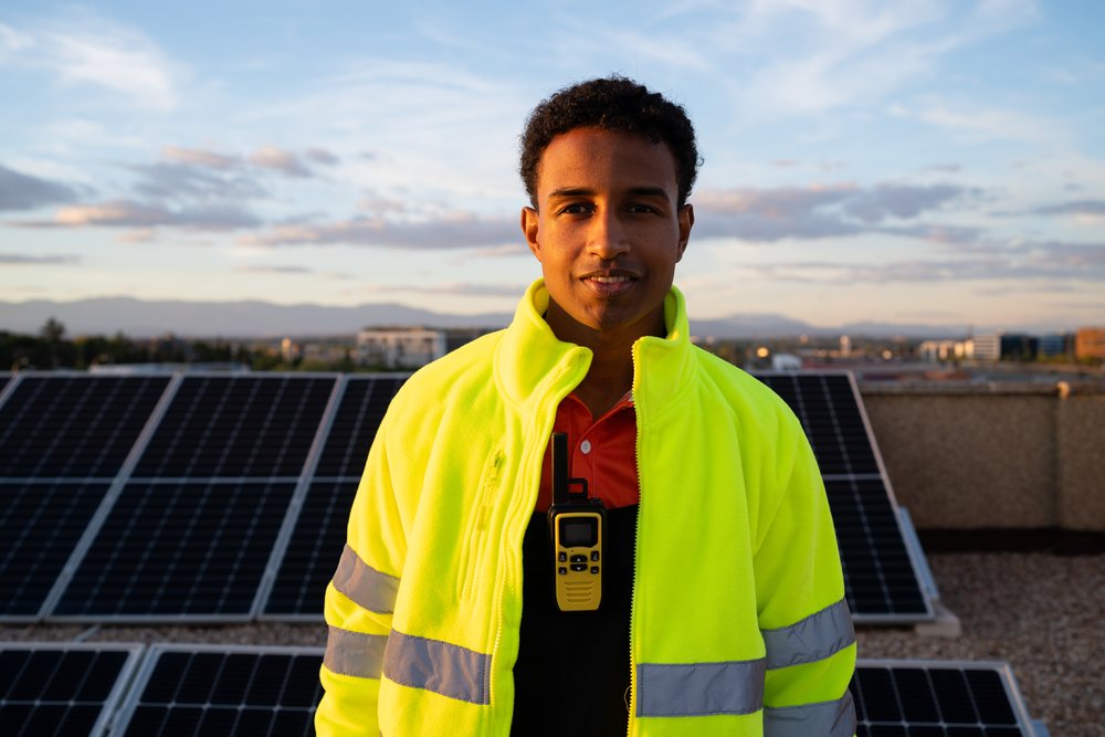 Worker in high-visibility jacket on rooftop solar panels
