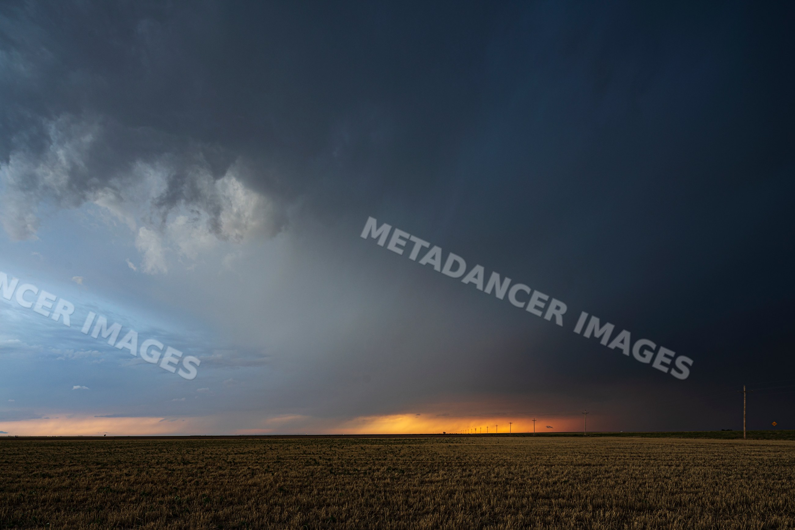 Storm clouds gather over field at sunset in ulysses, kansas