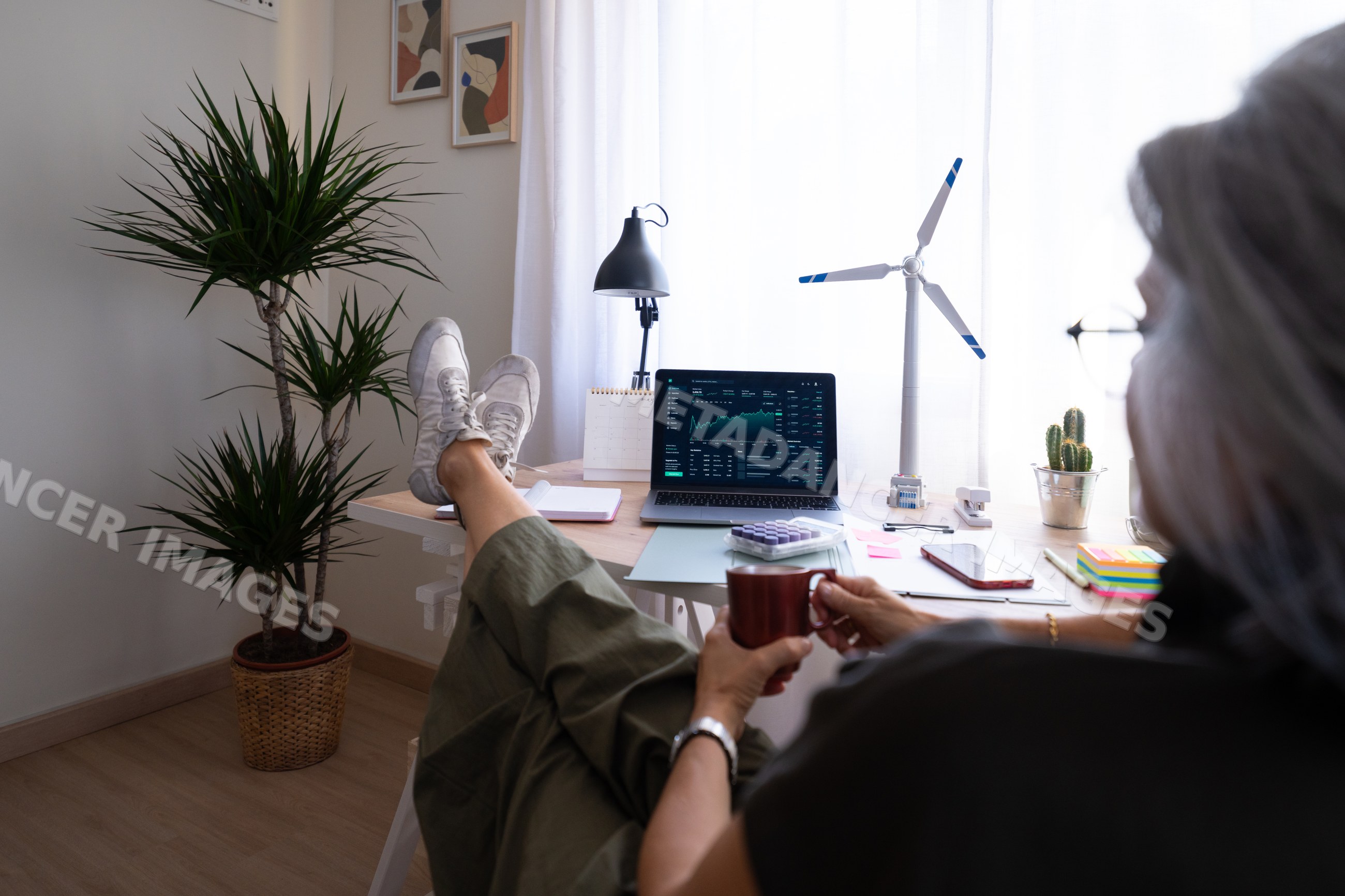 White person relaxing at home office desk with laptop