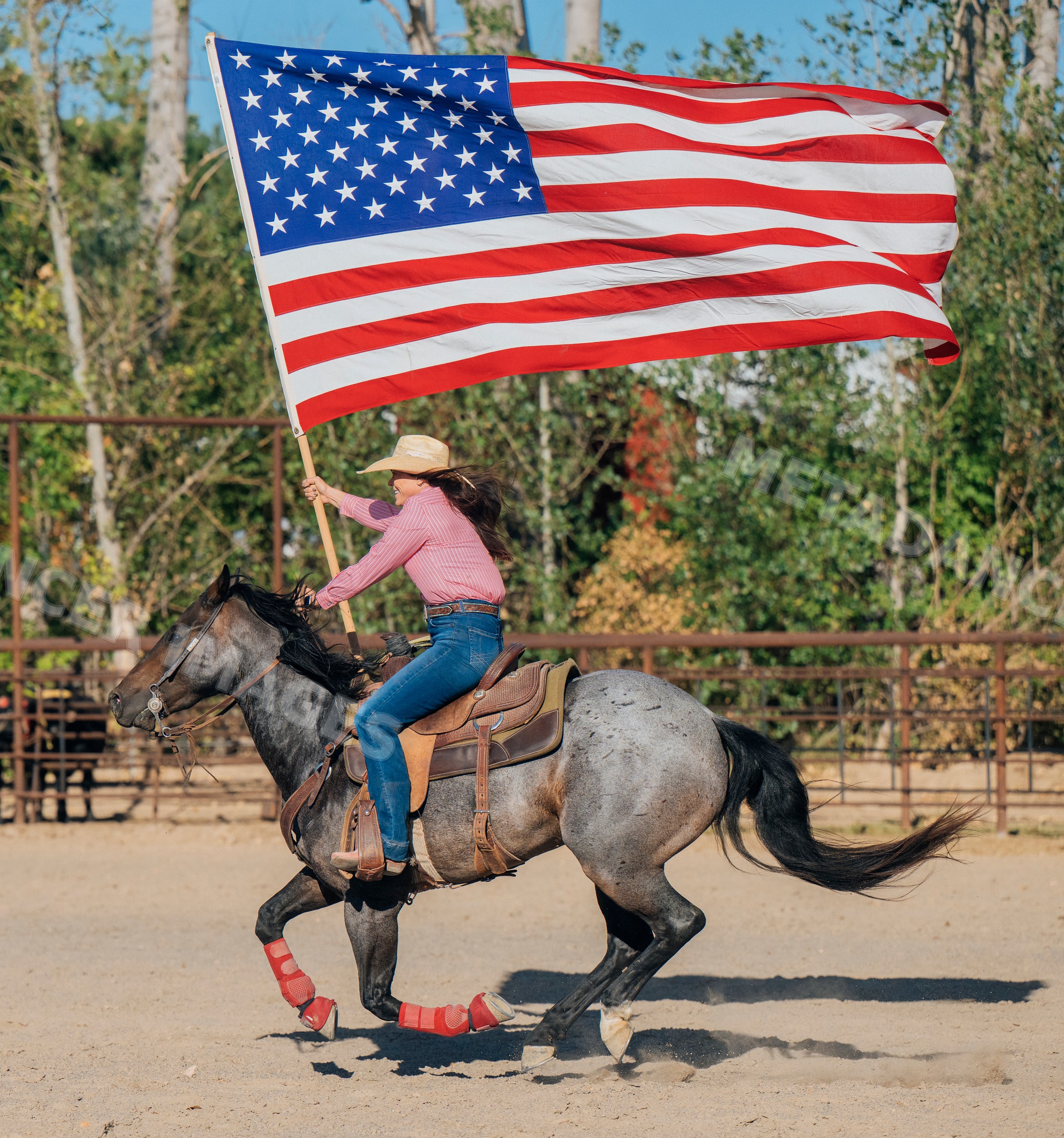 White woman riding horse holding american flag in western arena