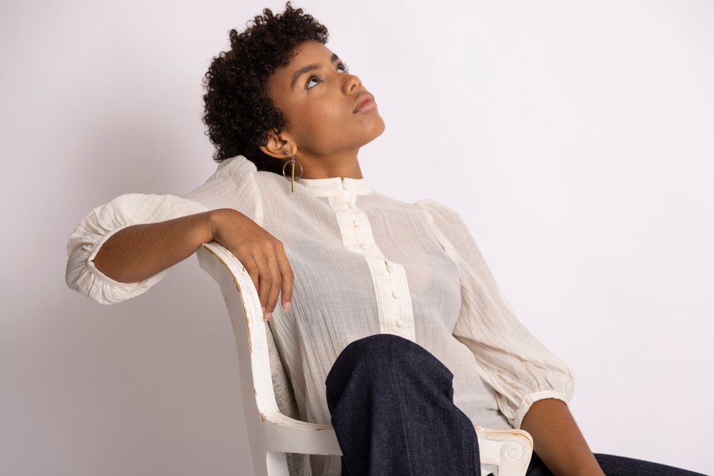 Hispanic woman sitting on white wooden chair looking upward