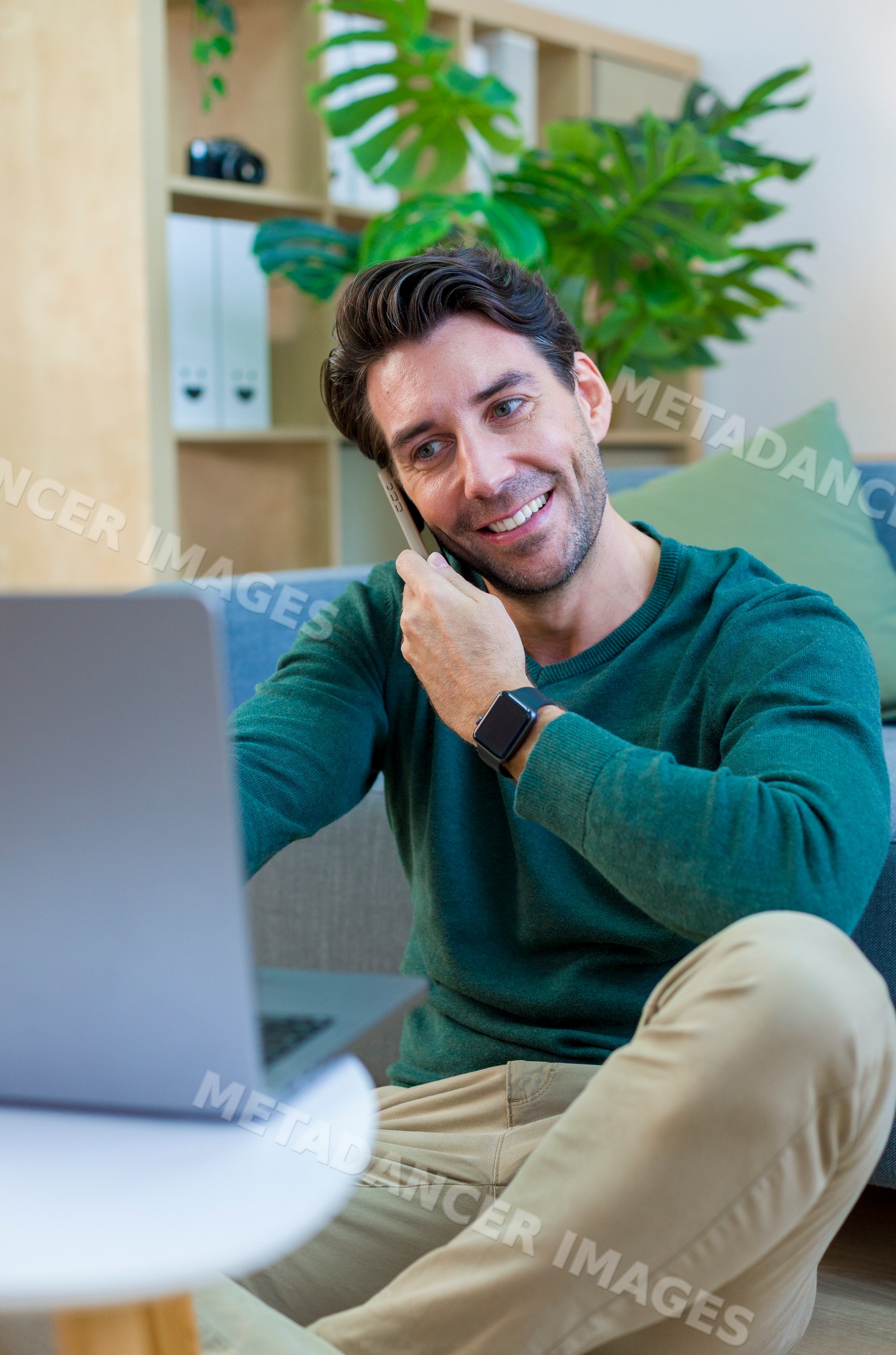 White man working at home with laptop and phone in modern interior